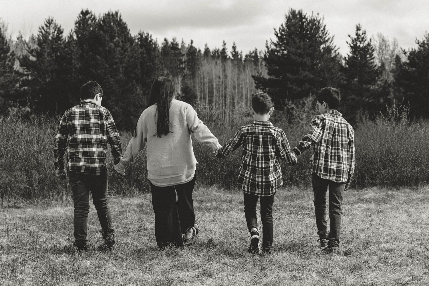 Four people standing together looking at a scenic forest view in matching plaid shirts.