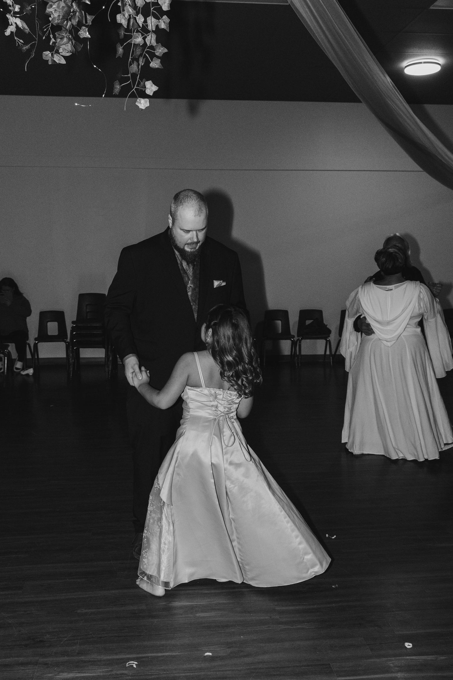 A black and white capture of a dance moment at a formal celebration with hanging decor.