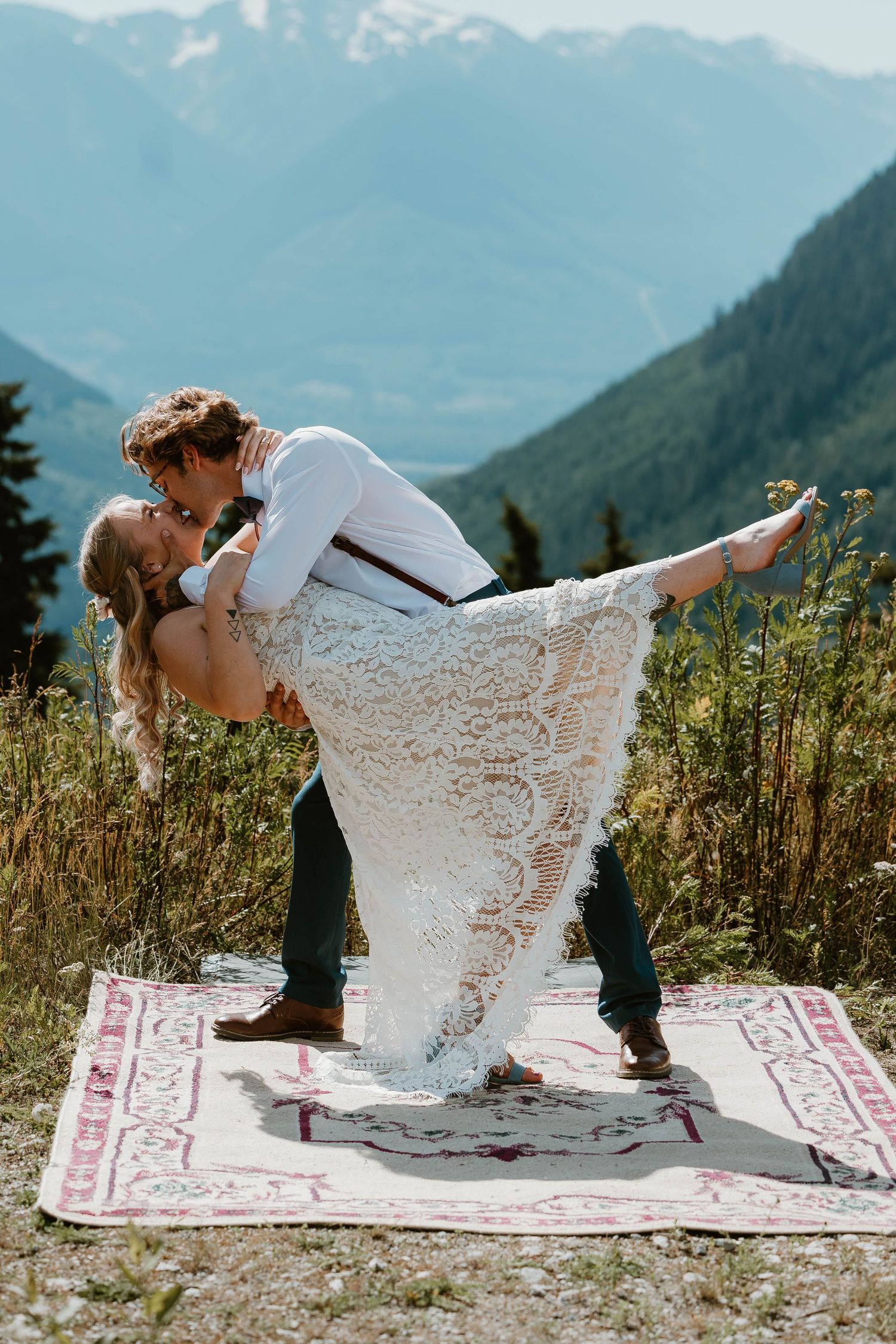 A romantic mountain elopement with a couple dancing on a rustic rug against a backdrop of snow-capped peaks.