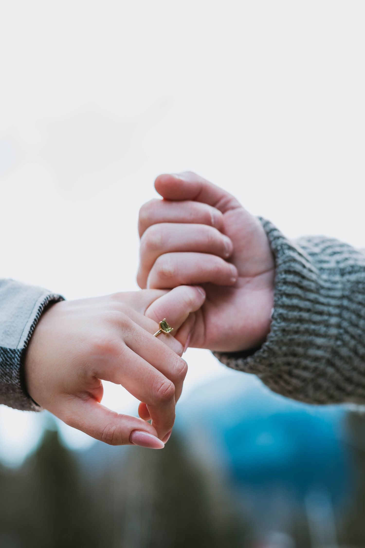 Close-up of two hands holding each other tenderly with a knit sweater in frame.