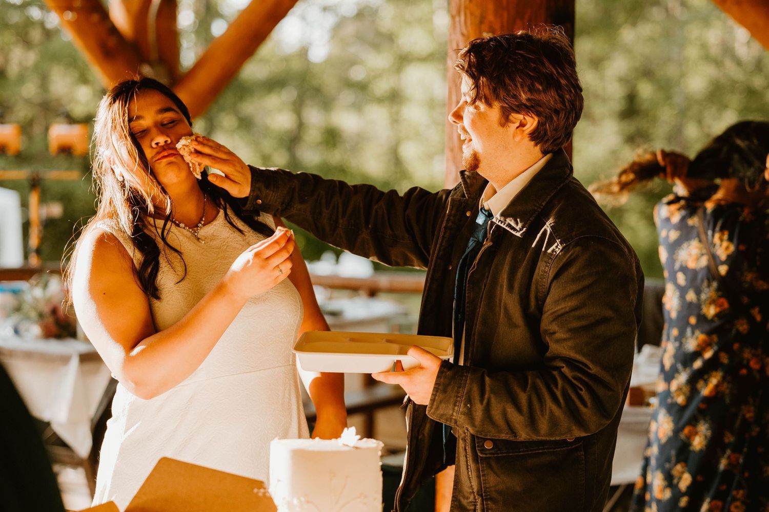 A joyful wedding moment as a couple feeds each other cake at their reception.