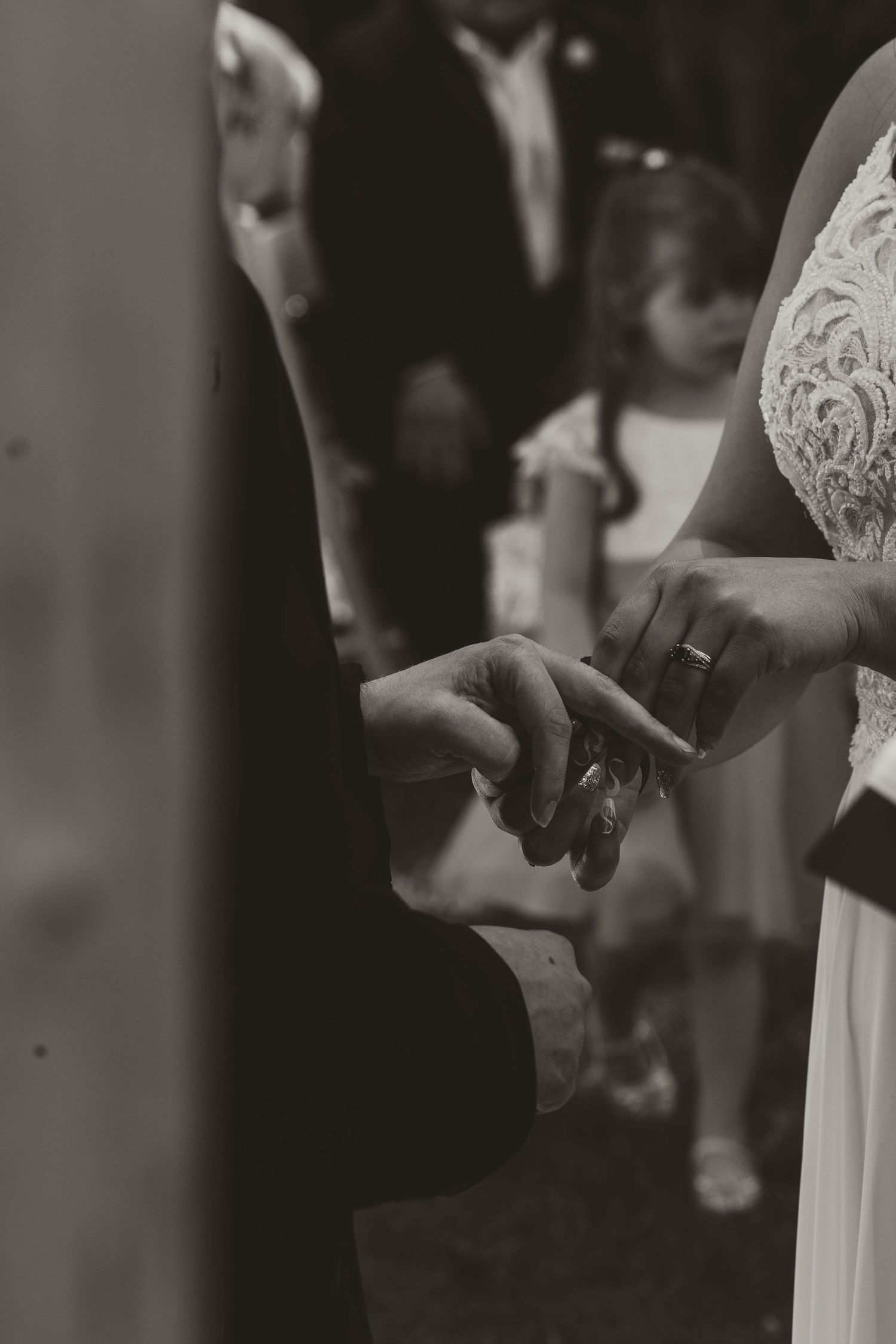 Black and white close-up of wedding rings being exchanged during the ceremony.