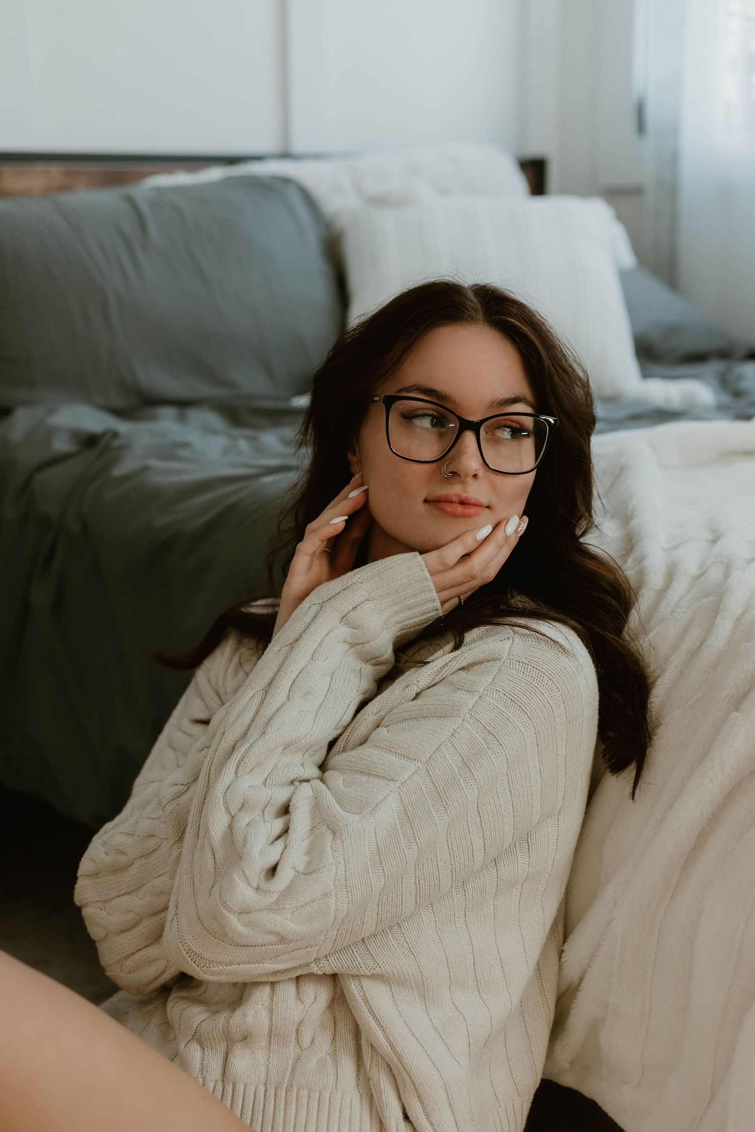 Person in cozy cable knit sweater relaxing on gray couch.