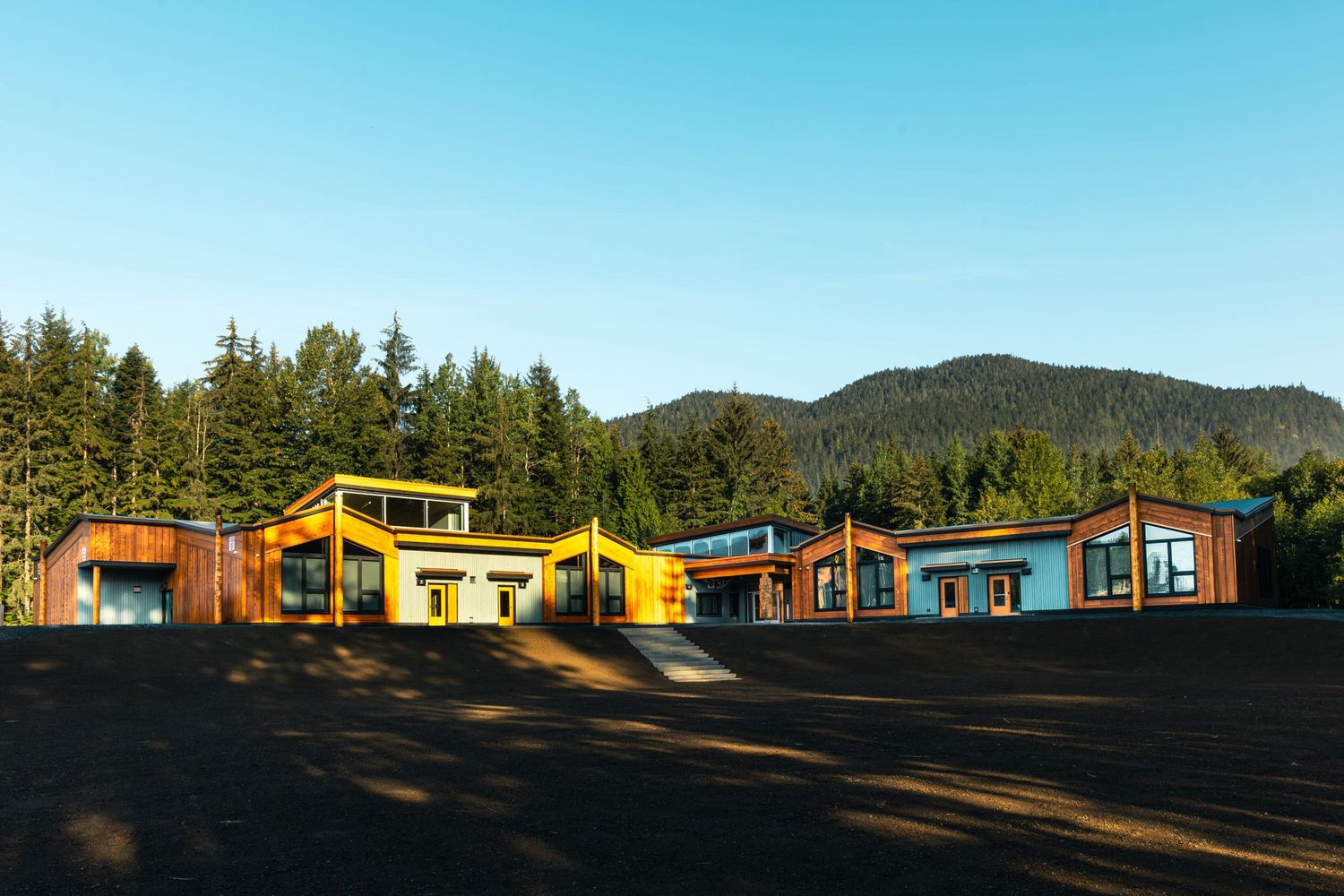 Modern colorful buildings nestled among evergreen trees in a mountainside setting.