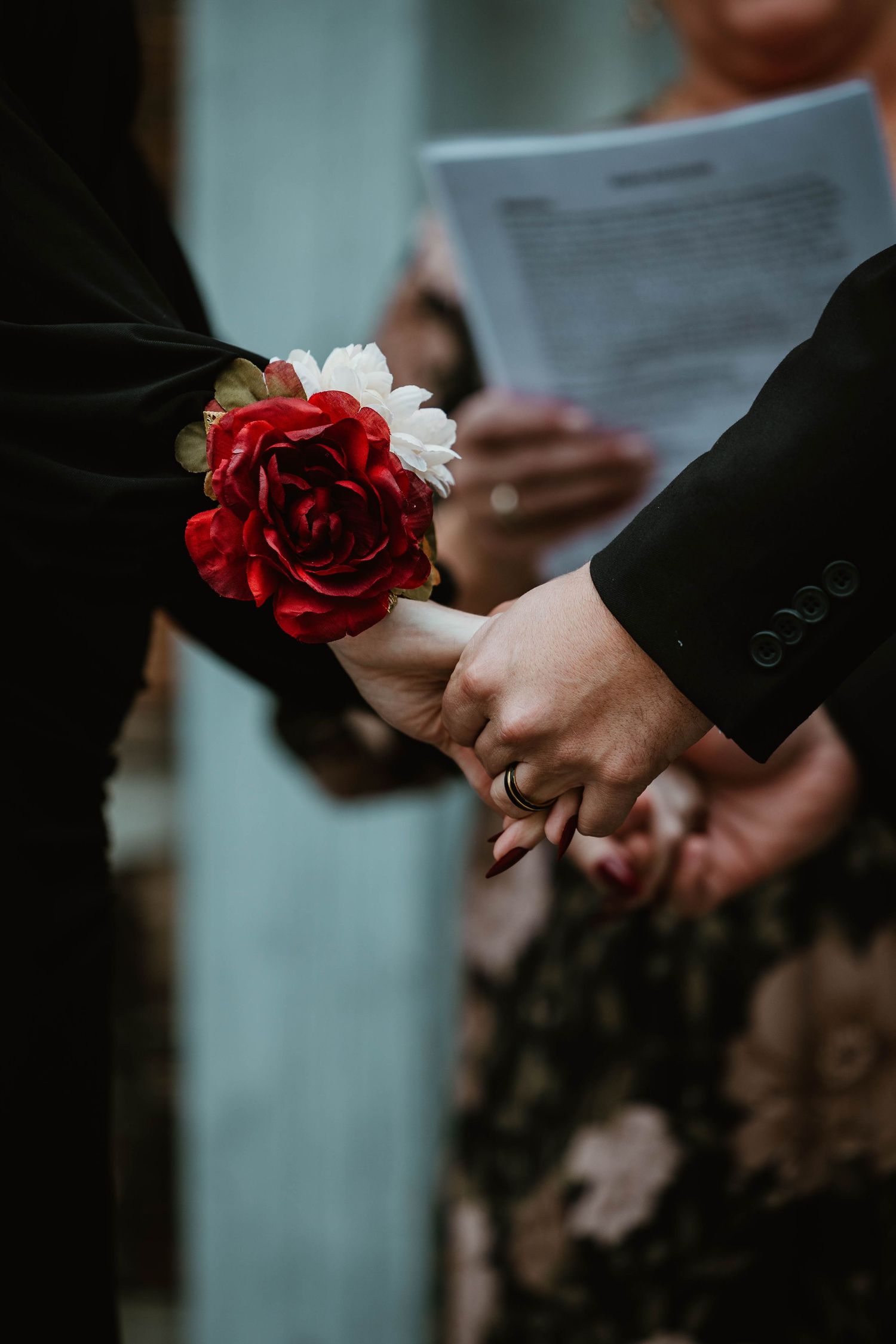 A red rose and white corsage being exchanged during a wedding ceremony.