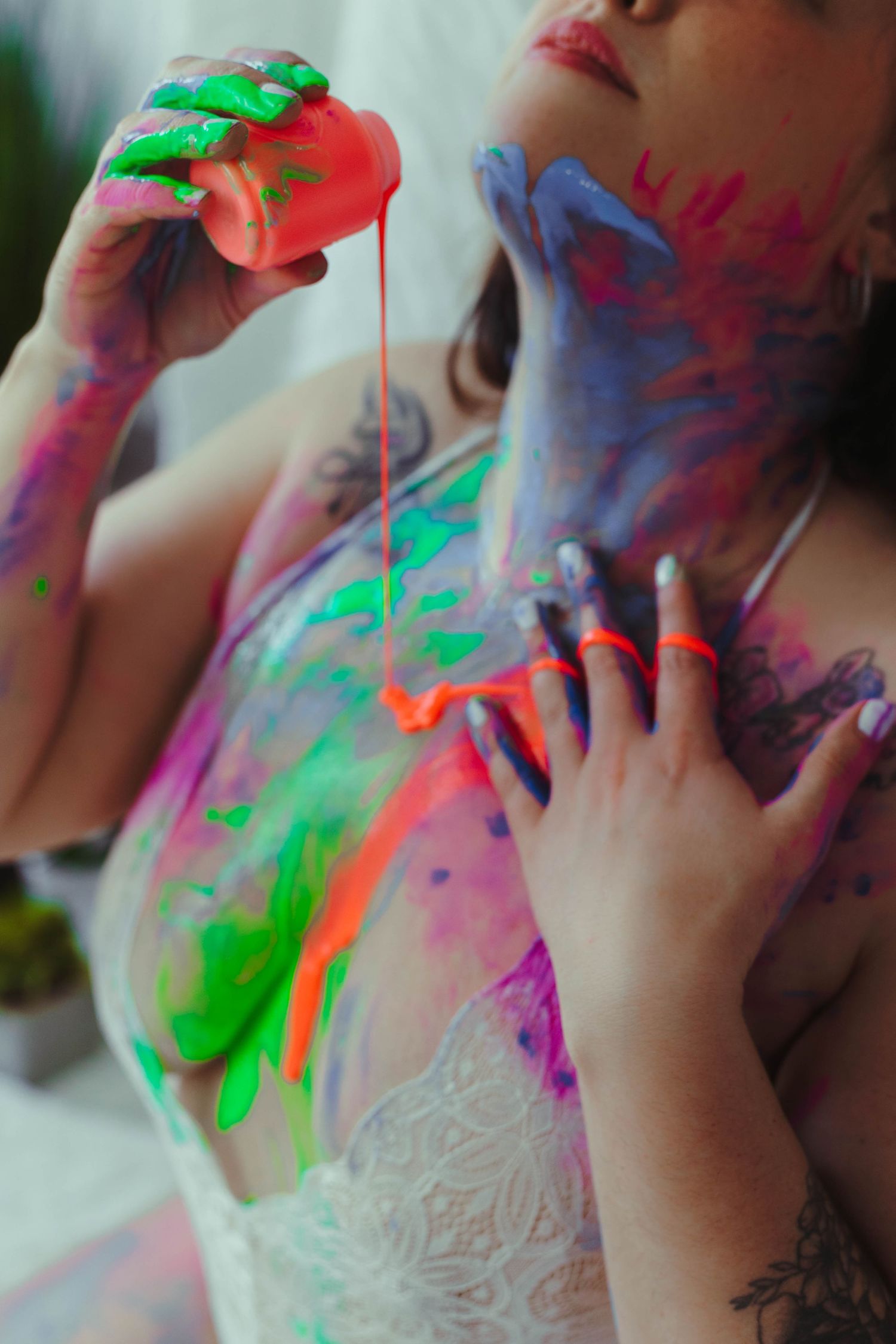 Abstract shot of neon body paint dripping in vibrant green, orange and pink colors.