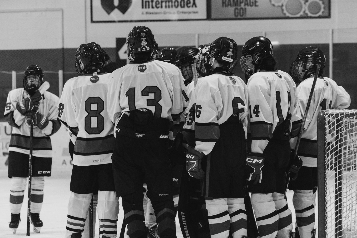 Vintage black and white photo of hockey team huddled together near goal net.