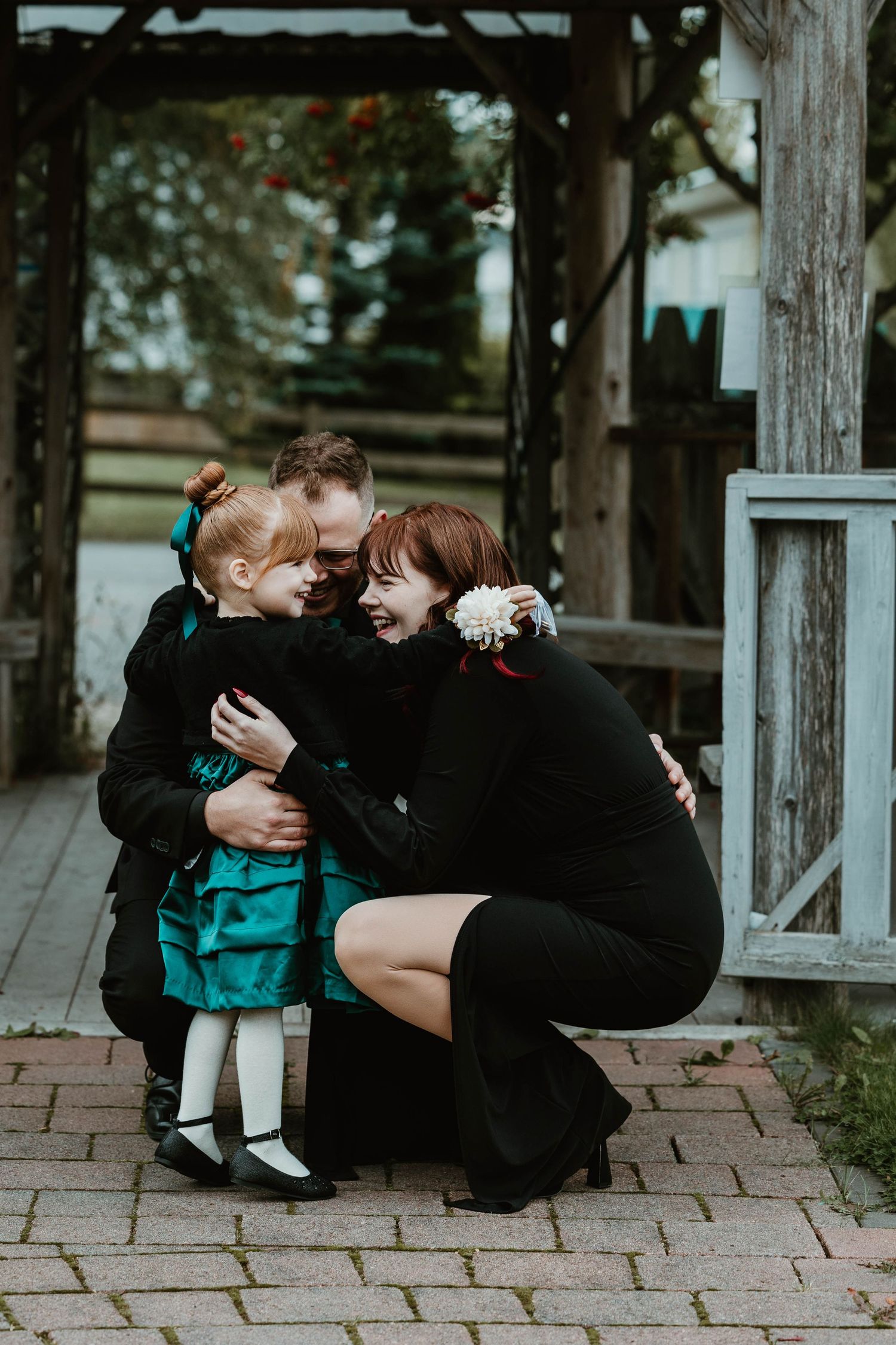 Tender moment shared under wooden gazebo with teal and black clothing.
