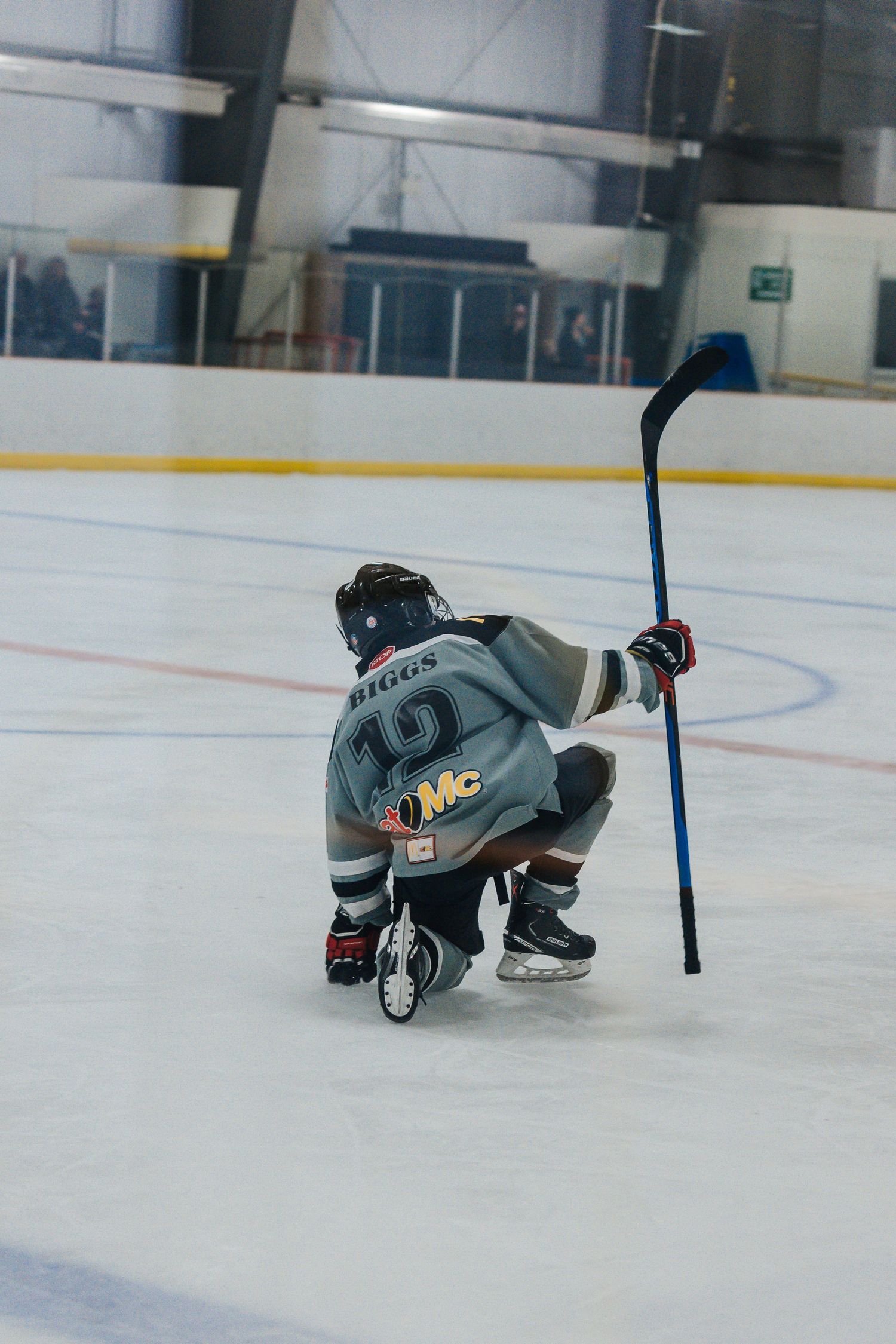 Hockey player bends down low on the ice while handling the puck during practice.