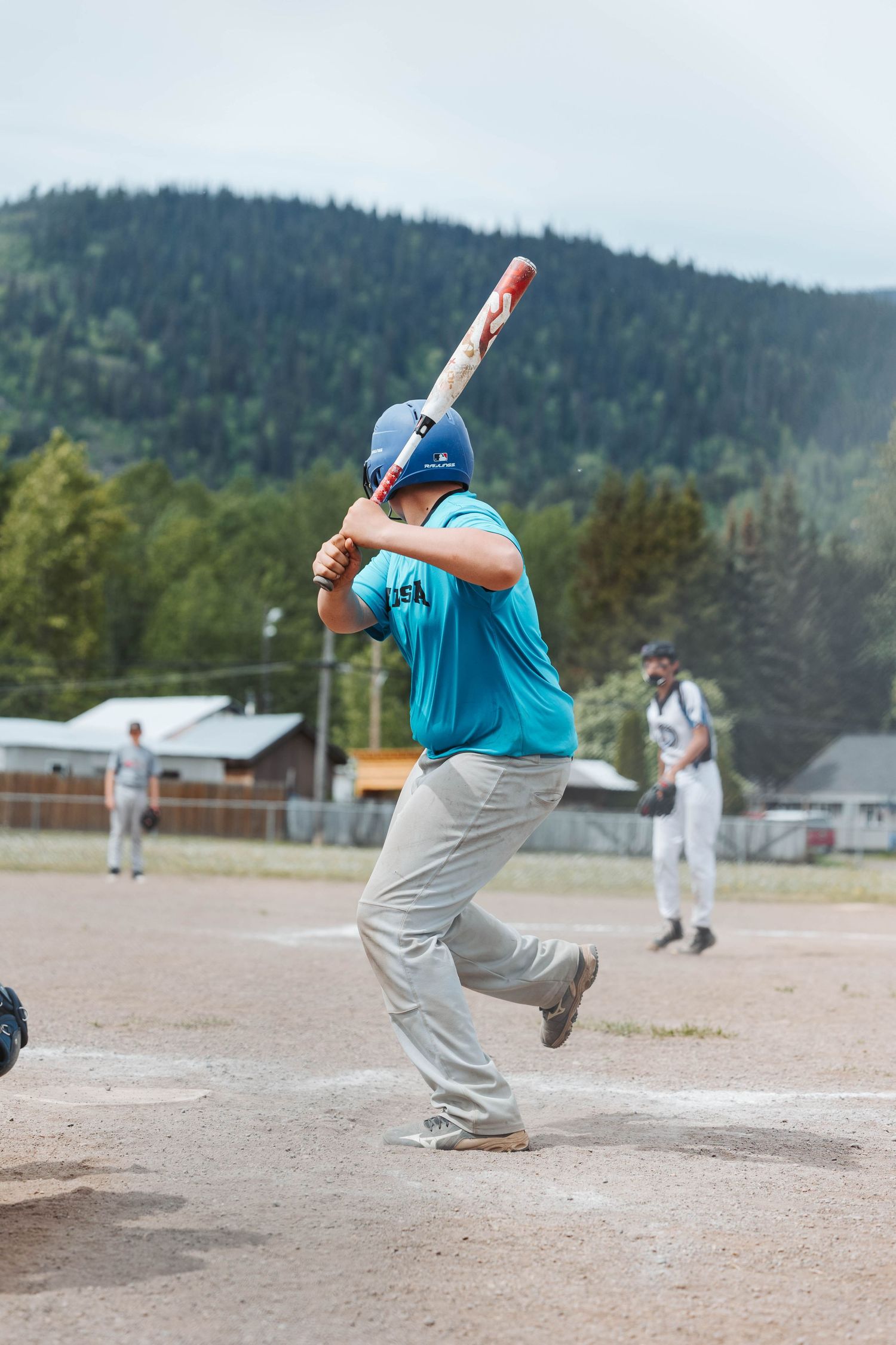 Baseball batter in teal jersey follows through on swing during game.
