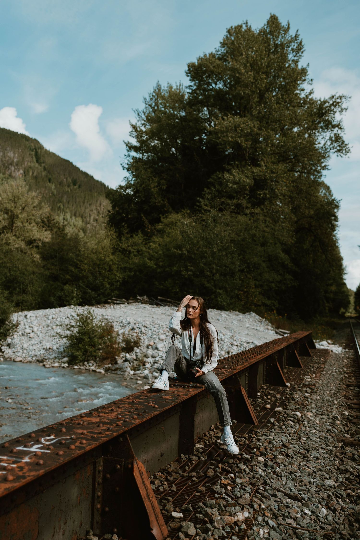 A scenic portrait on rustic train tracks with mountains and trees in the background.