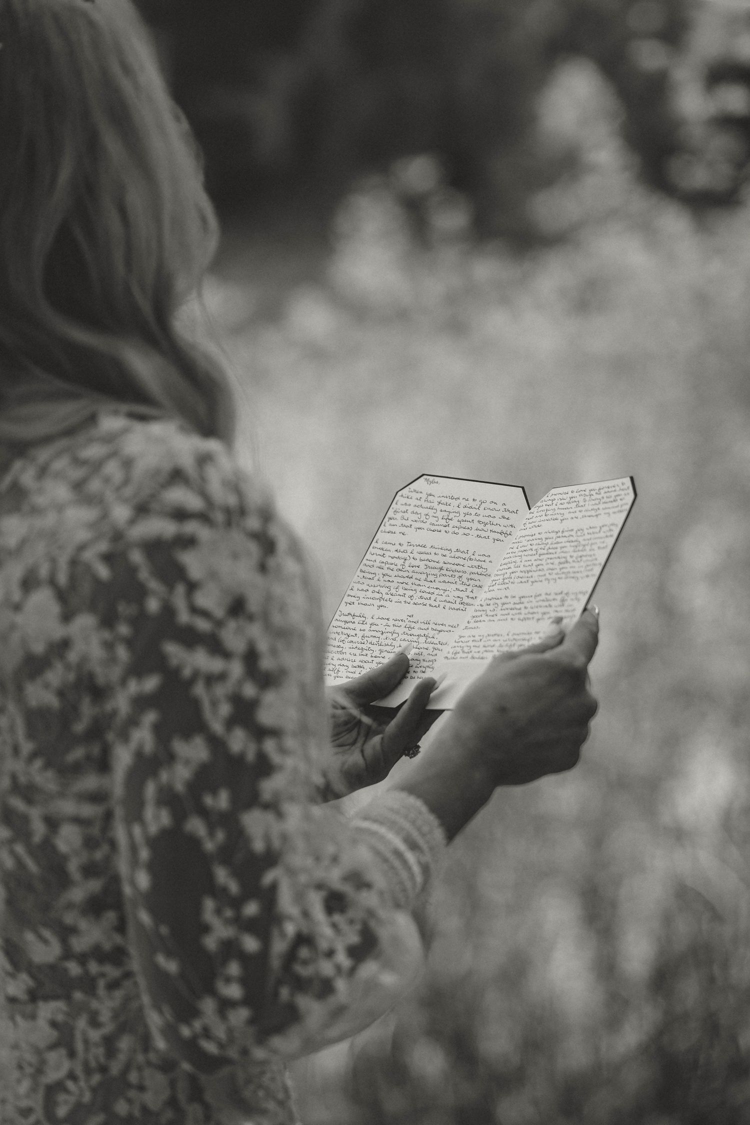 A person in floral clothing reads a book outdoors in black and white monochrome style photography.