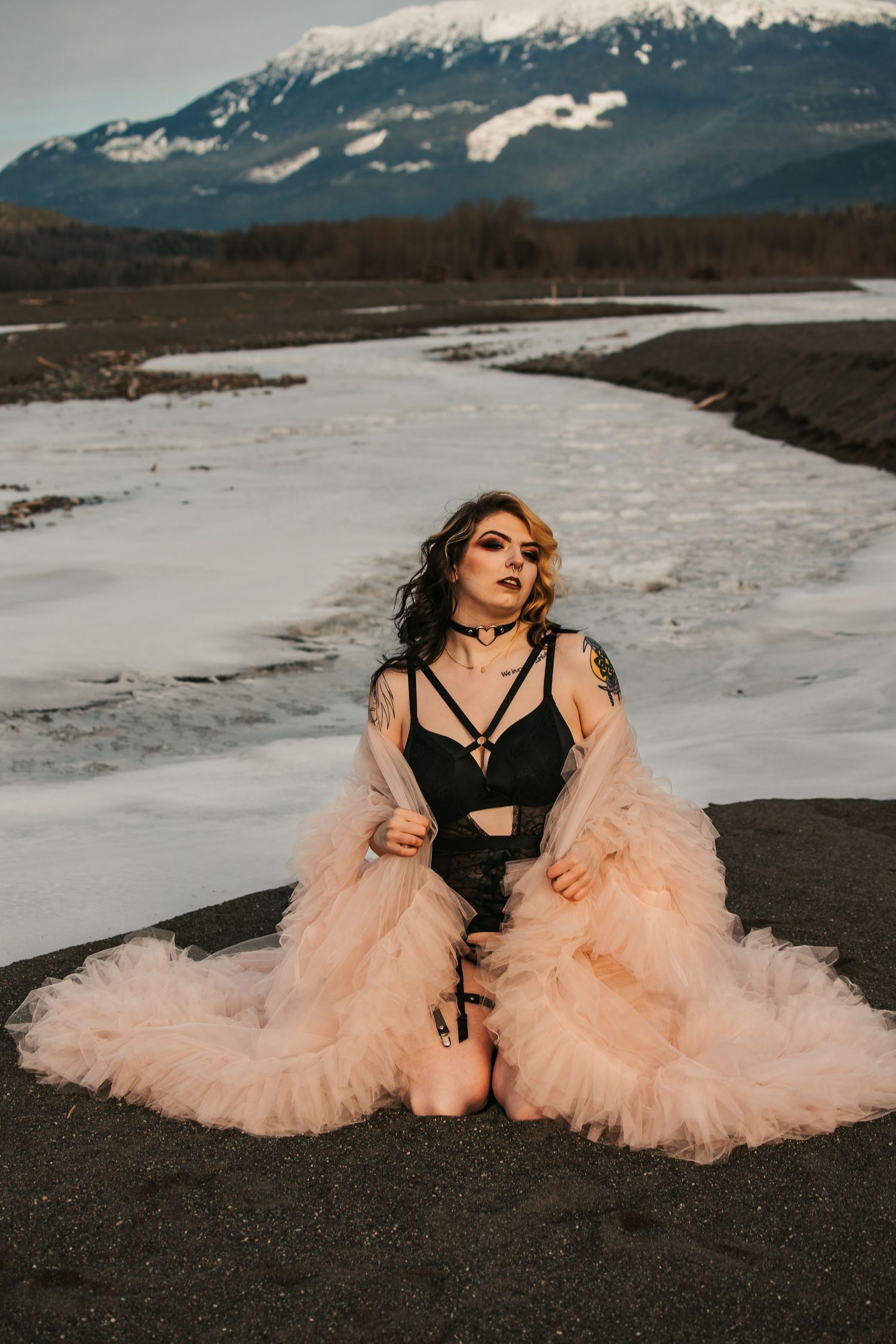 Dramatic fashion shoot with peach tulle gown against snowy mountain scenery.
