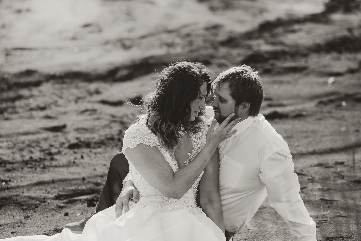 Black and white photo series showing a romantic couple embracing and kissing on a beach at sunset.
