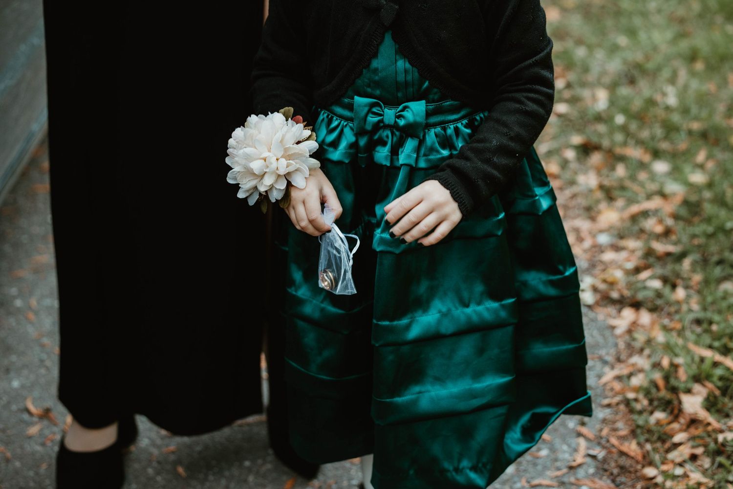 Hands holding a white carnation flower against dark clothing.