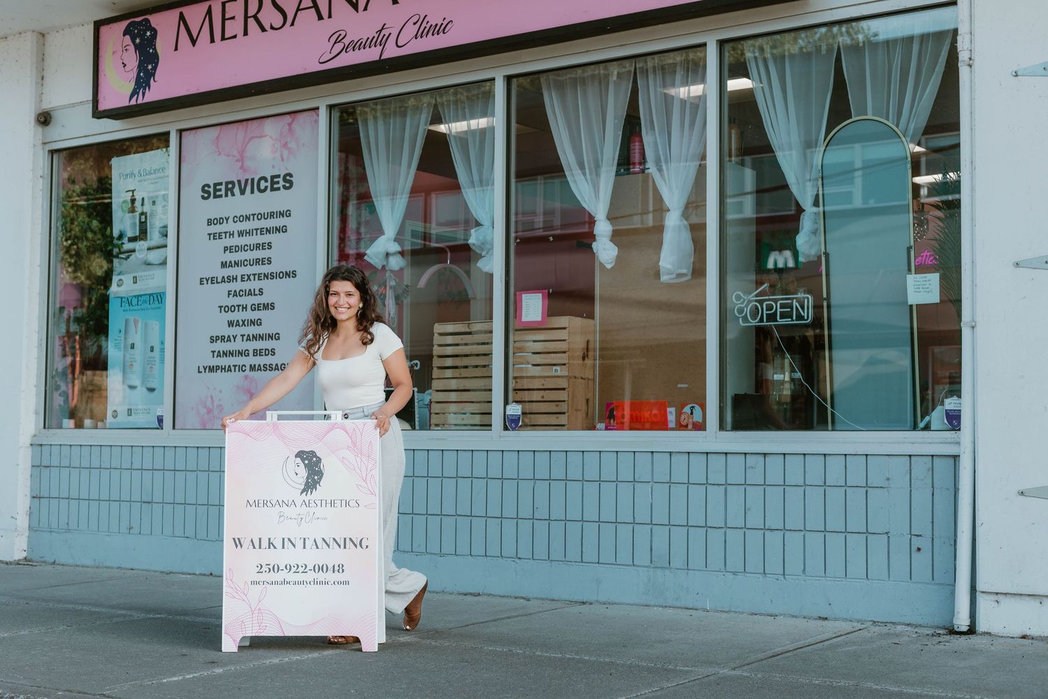 Storefront of Mersanj boutique with teal accents and white curtains.