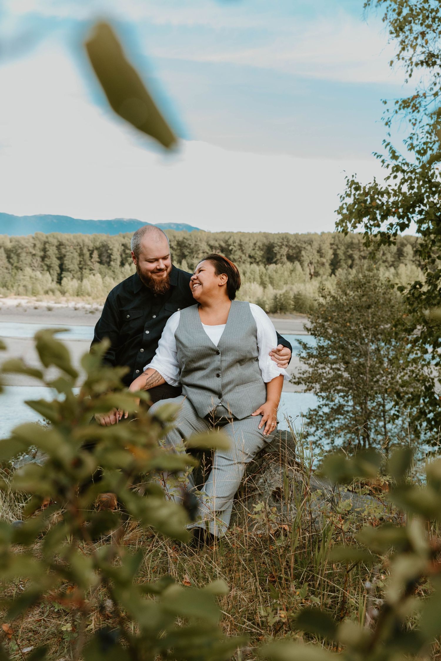 A couple sharing a lighthearted moment together in a scenic natural setting with mountains in the background.