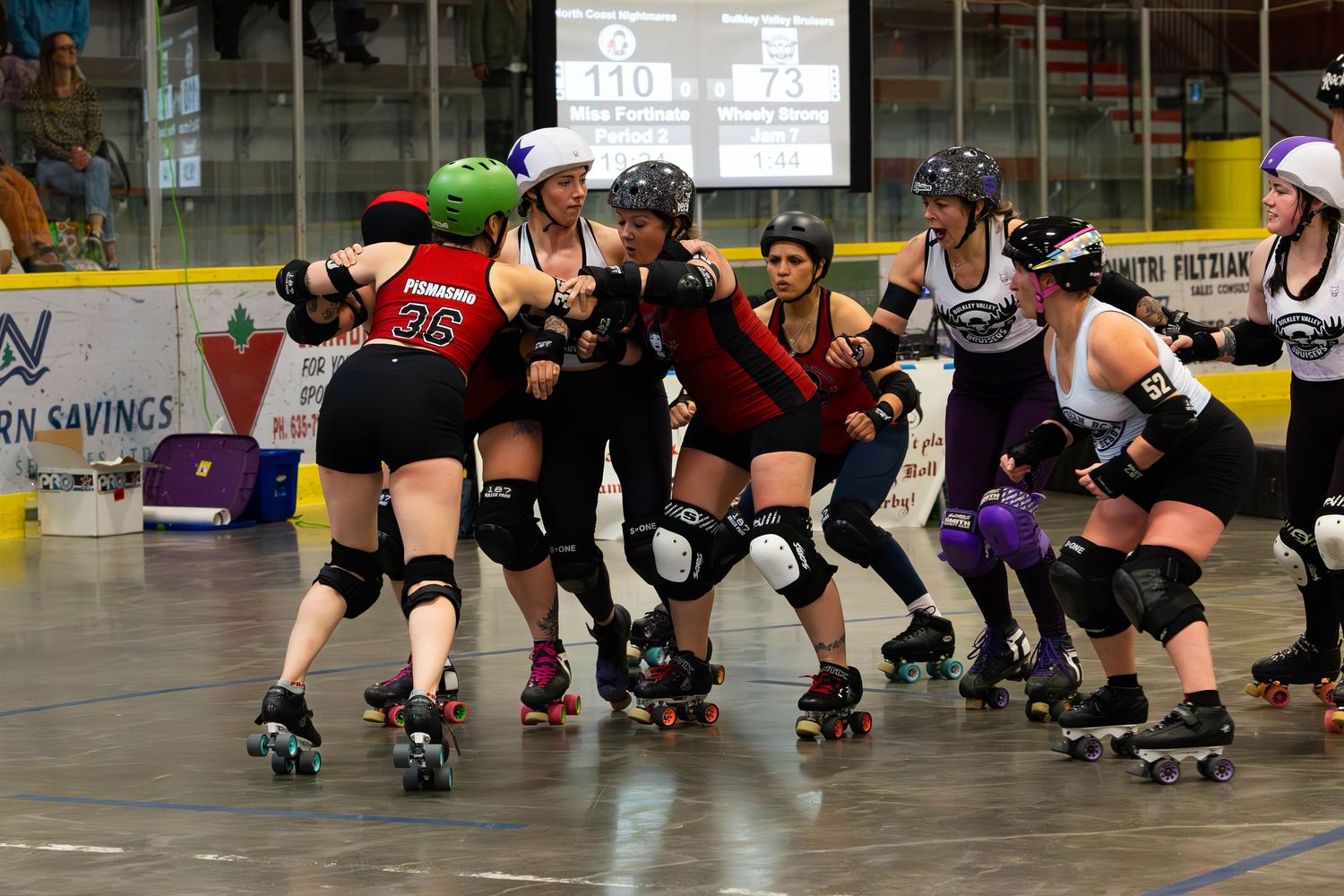 Roller derby players competing in an intense match on indoor skating rink.