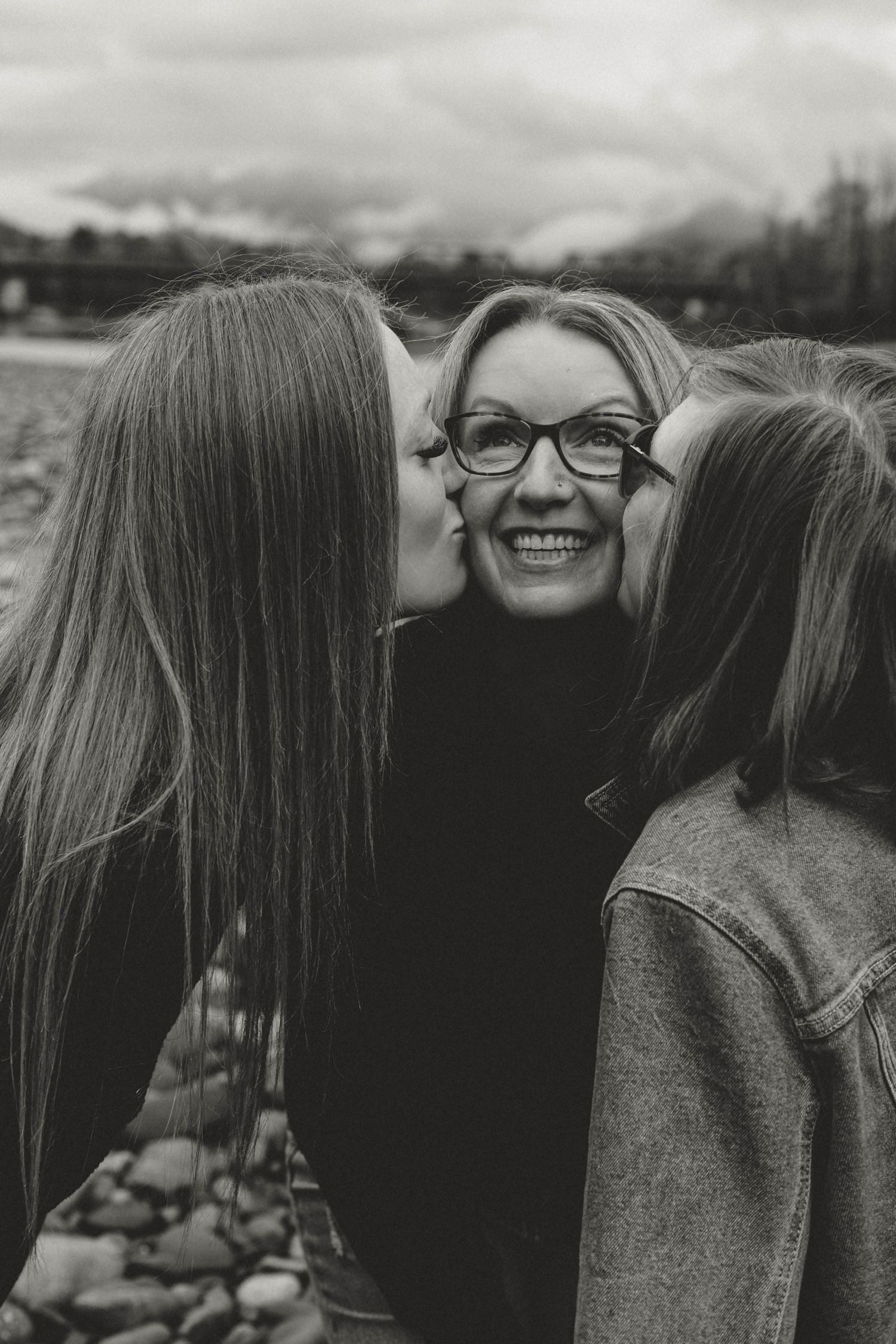 Black and white candid moment of affectionate kisses being shared between friends.