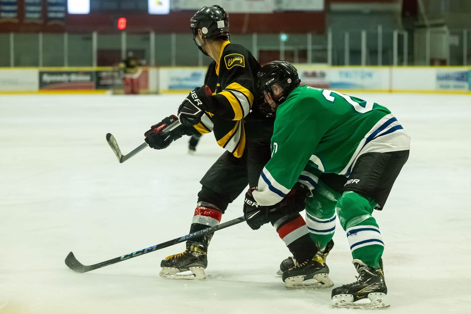 Players in green and black jerseys battle for puck possession during an ice hockey match.