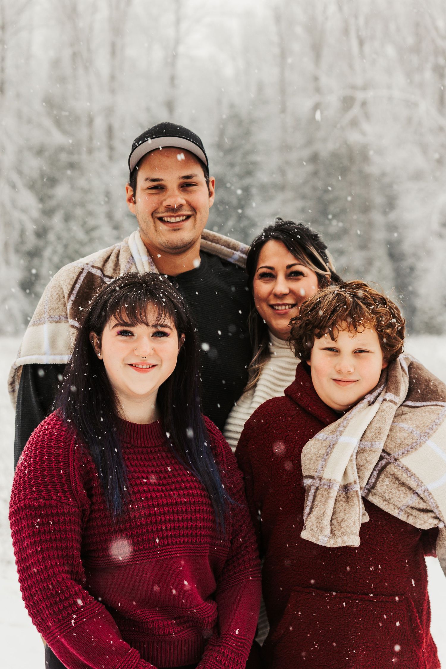 A winter portrait of a group in warm sweaters enjoying a snowy day in the forest.