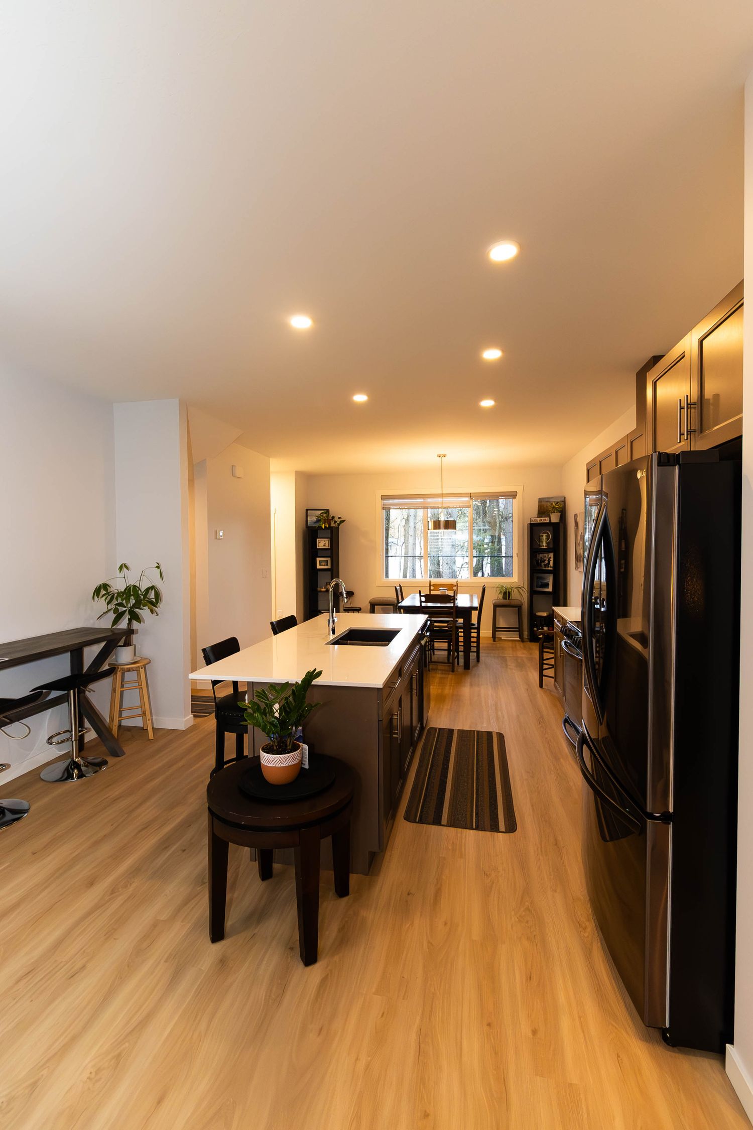 Modern open-concept kitchen with light wood floors, black appliances, and recessed lighting showcases a long island counter.