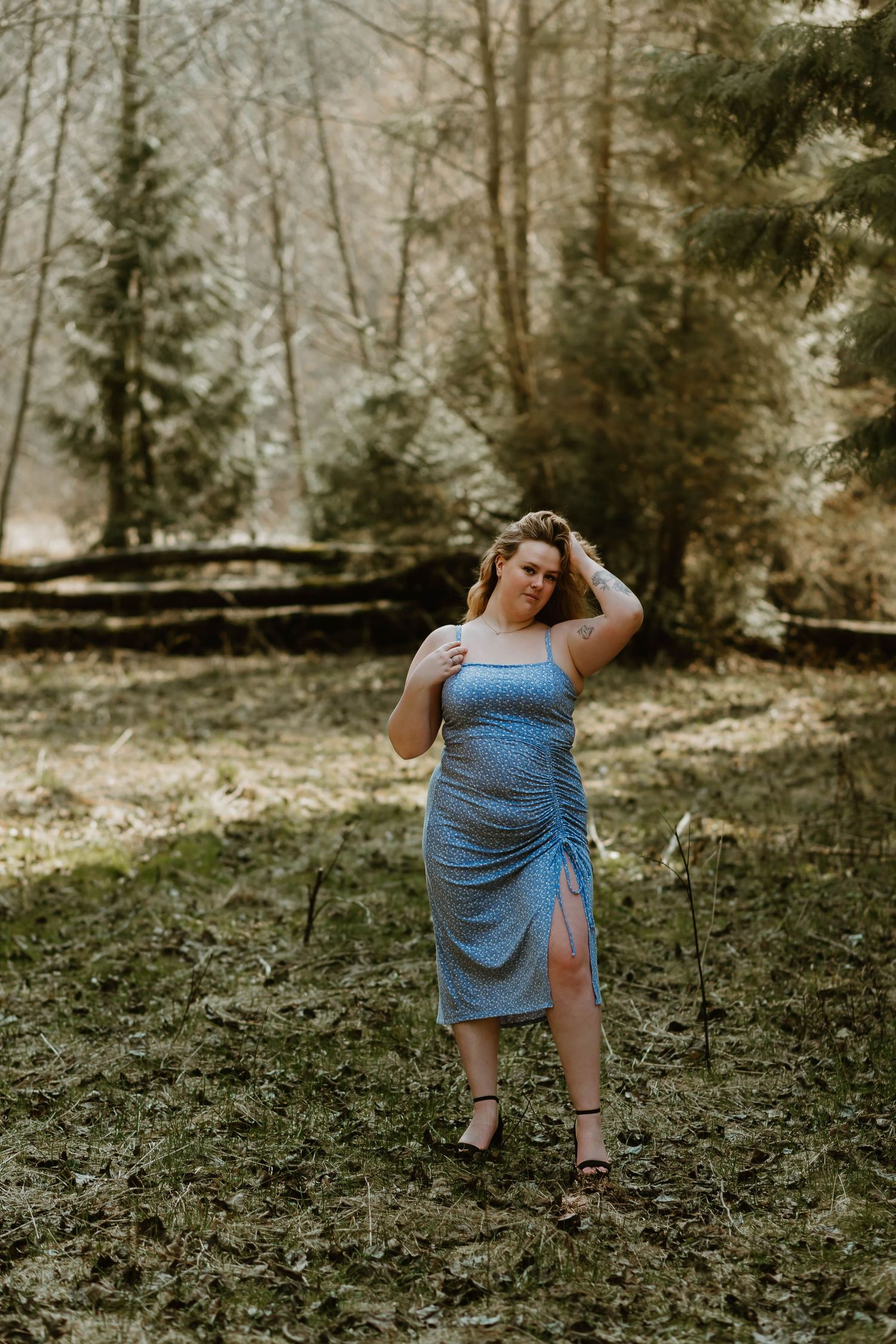 Flowing blue polka dot dress with side slit photographed in a scenic woodland setting during golden hour.