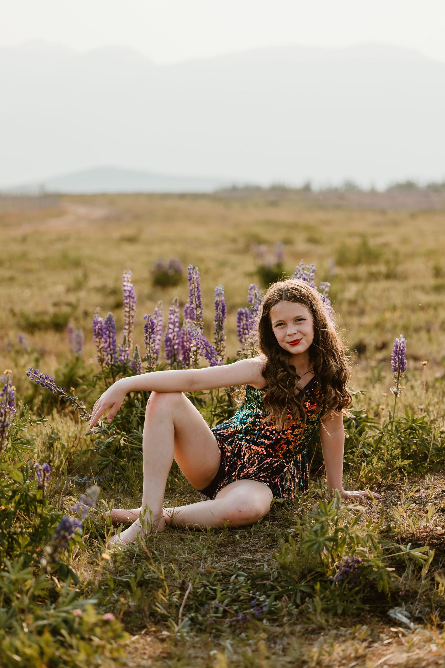 A floral summer portrait taken at sunset in a wildflower meadow with purple lupines and natural golden light.