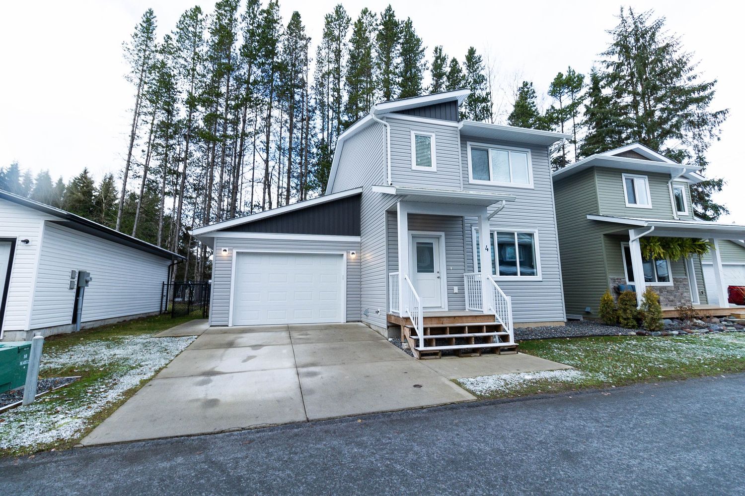 Two-story gray suburban house with attached garage and front porch on a winter day.