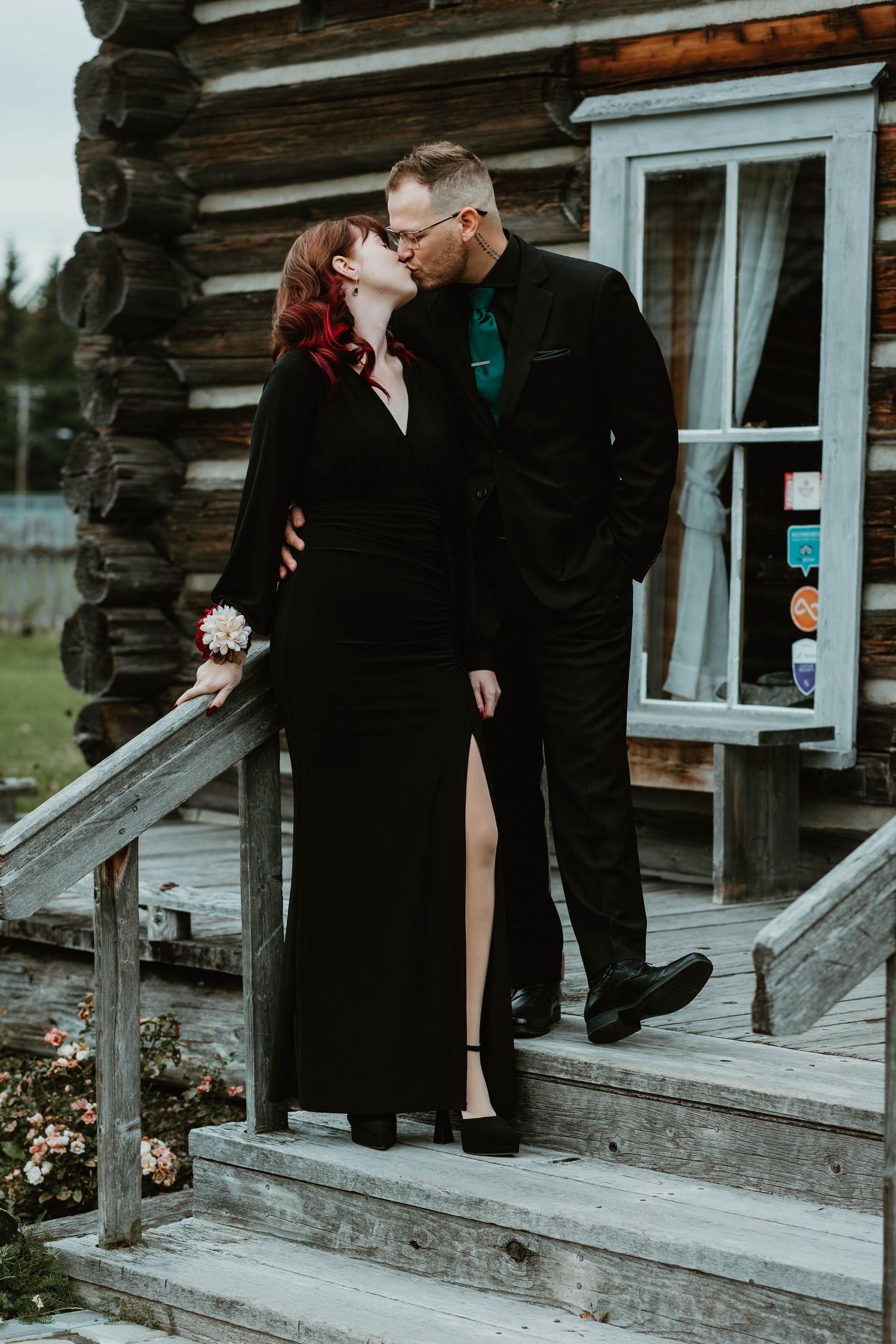 A romantic moment between a couple on wooden steps of a rustic cabin.
