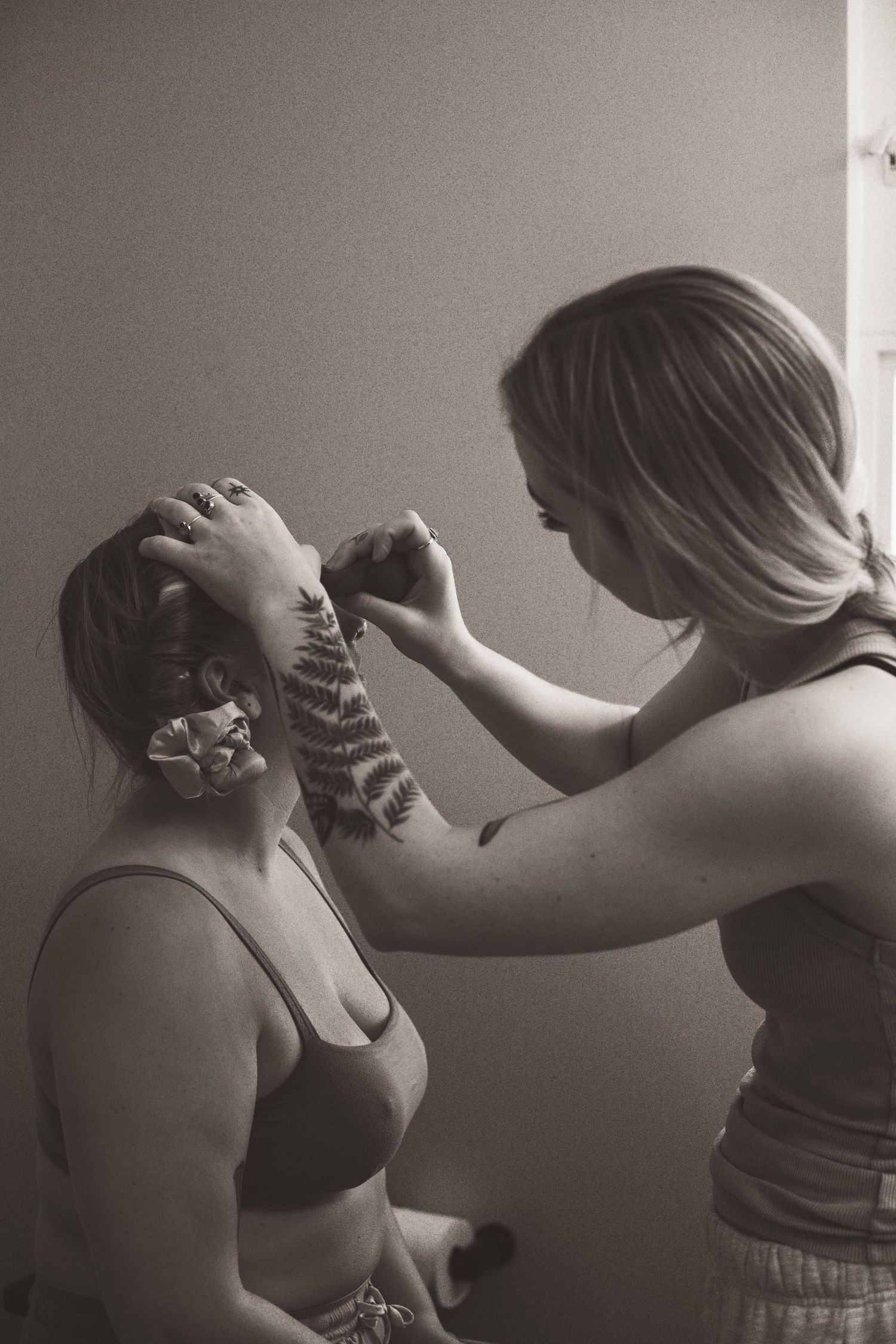 Black and white photograph of two people during makeup preparation.