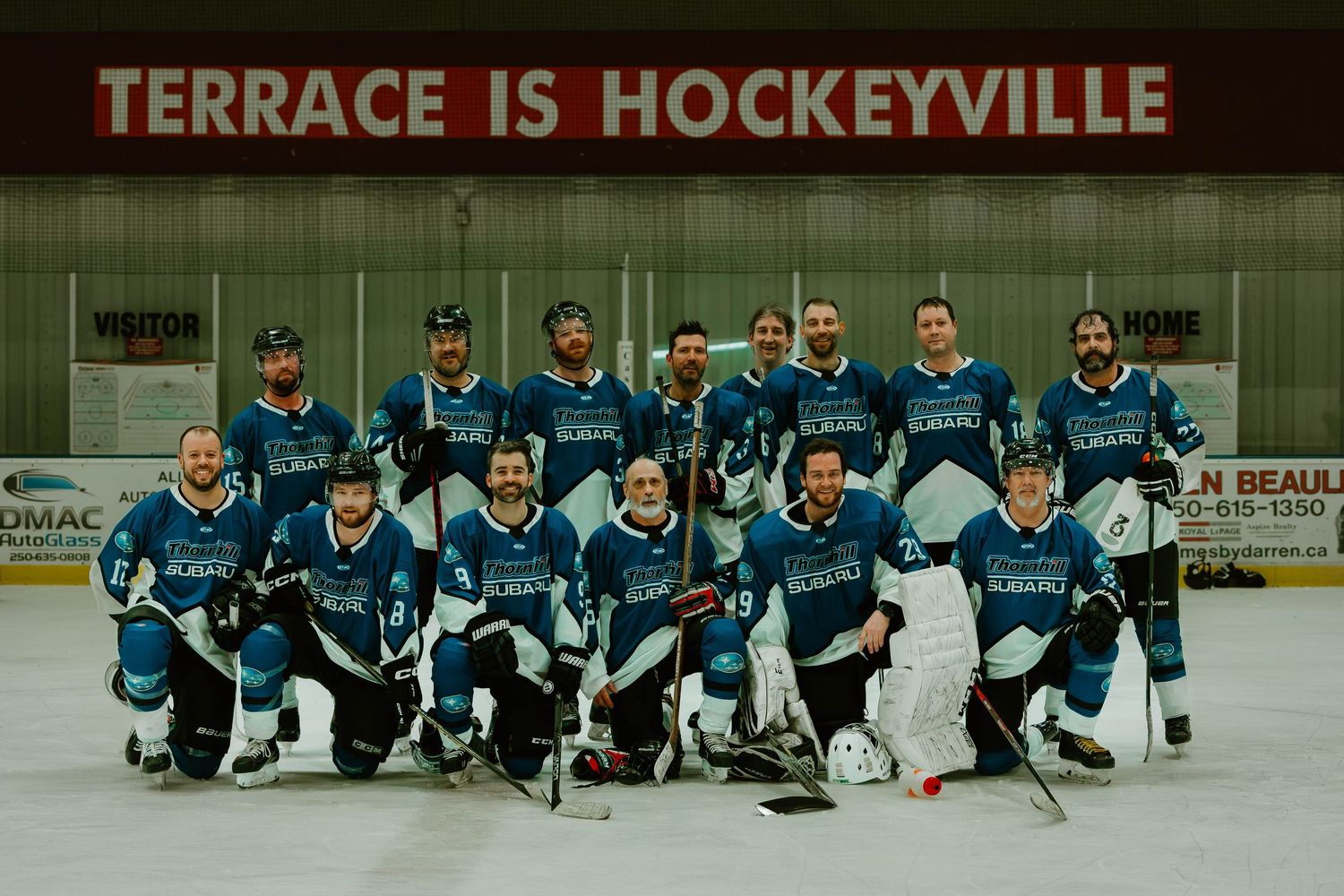 Hockey team in teal jerseys poses for group photo under Terrace is Hockeyville sign.