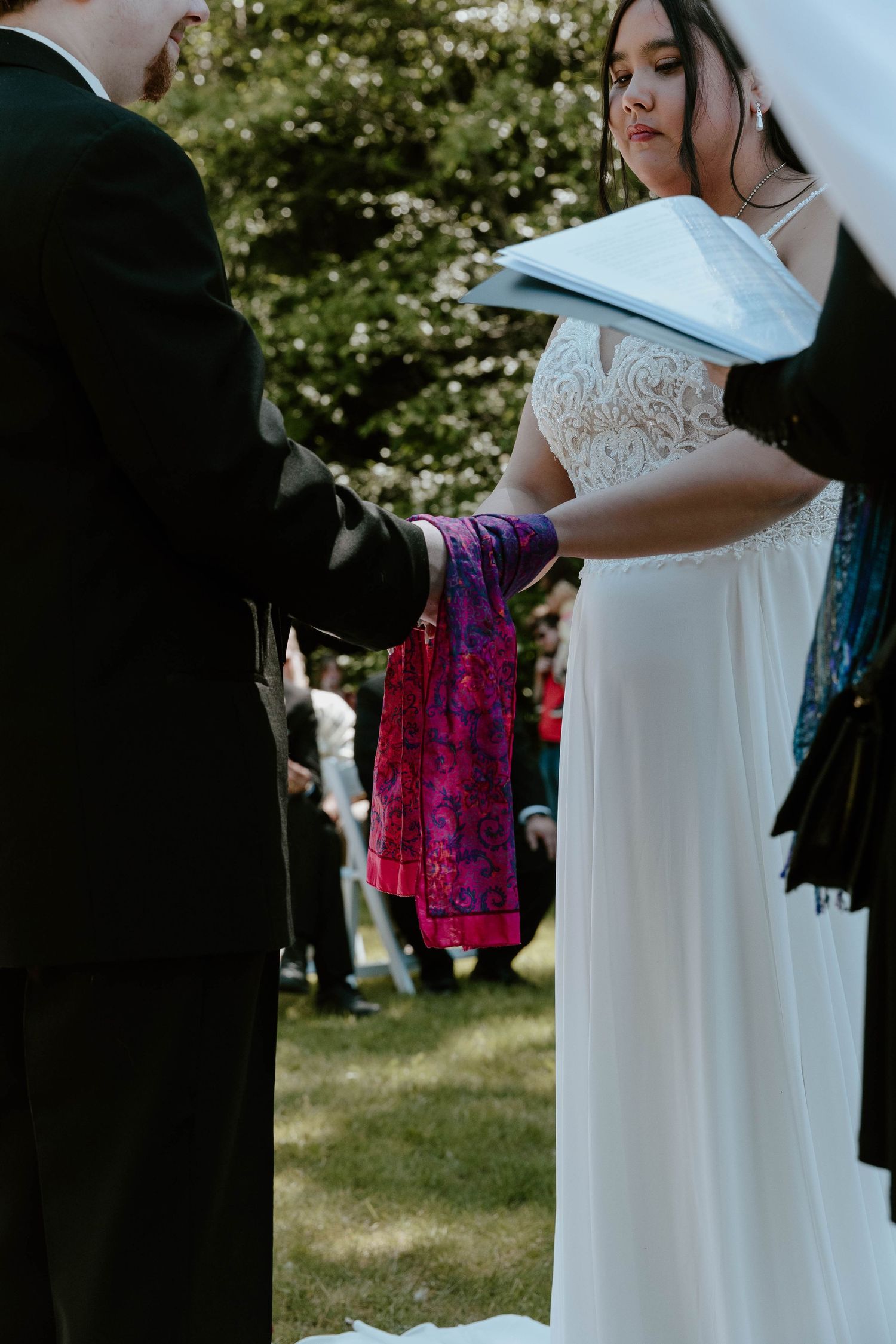 A wedding ceremony featuring a bright pink ceremonial cloth being presented during the service.