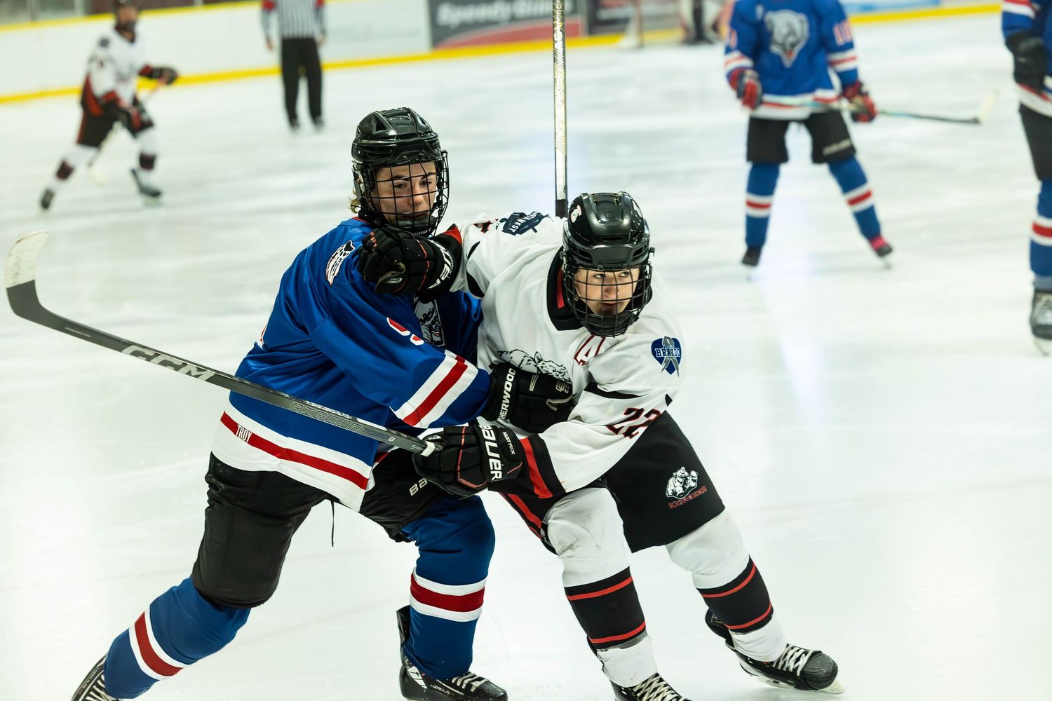 Youth hockey players competing for puck possession during game.