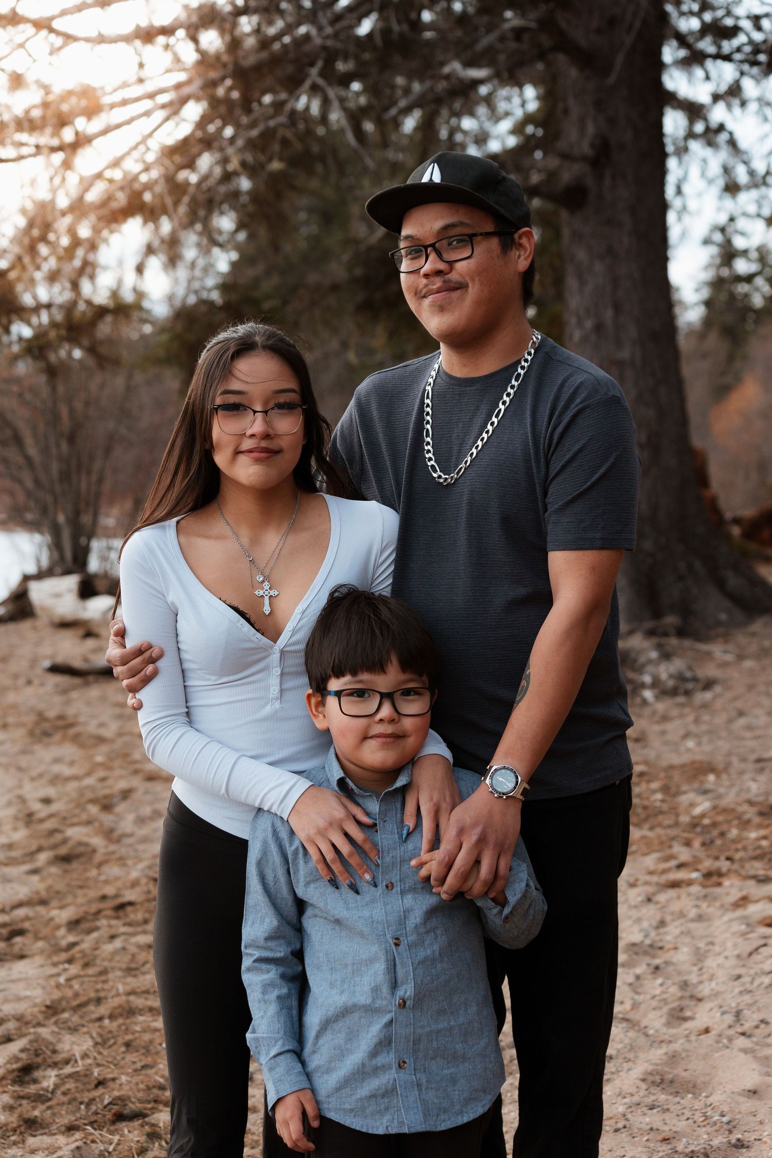 Family portrait in outdoor setting with warm sunset lighting through trees.
