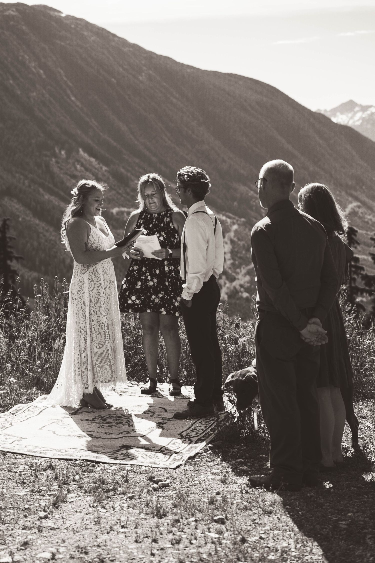 A black and white capture of an intimate mountain wedding ceremony with guests gathered around.