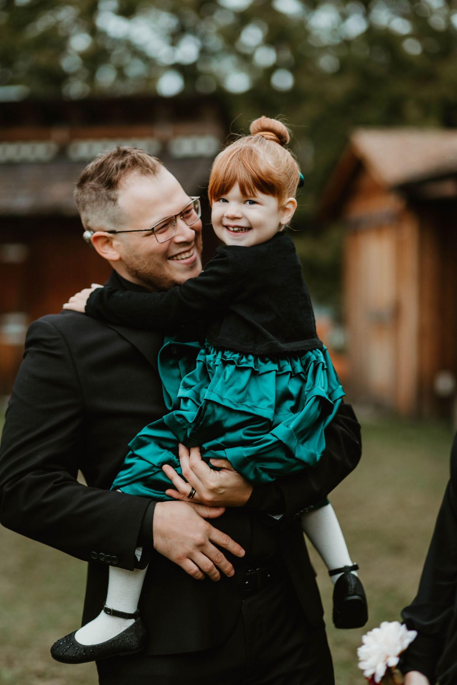 Candid family moment showing laughter and joy with small child wearing emerald green dress and white socks.