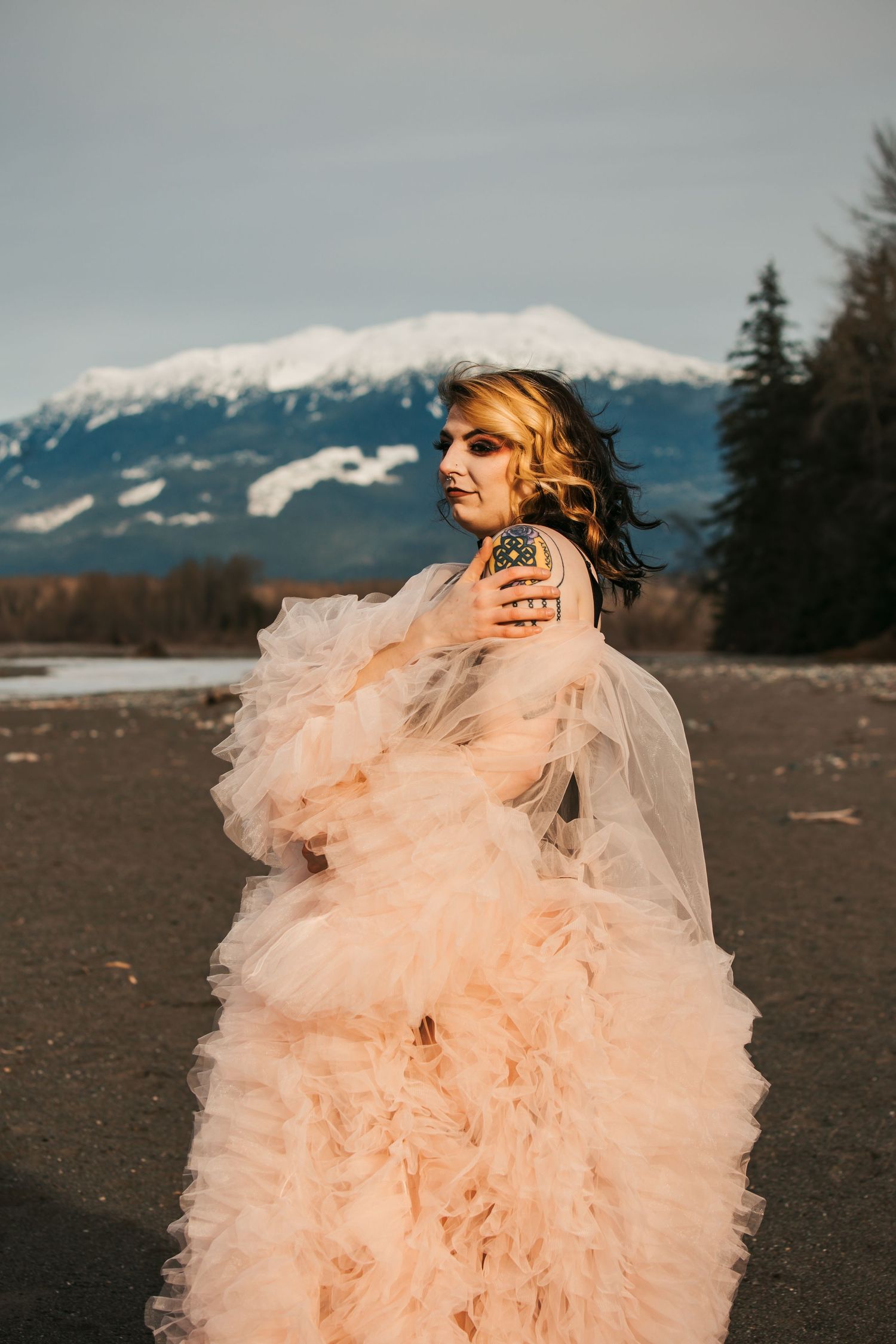 Ethereal portrait featuring a flowing peach tulle gown against snowy mountain backdrop.