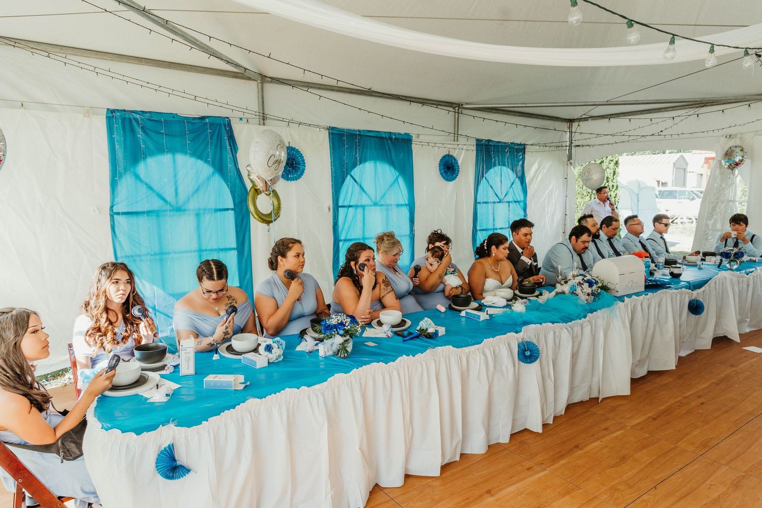Wedding reception with long table decorated in turquoise and white under tent.