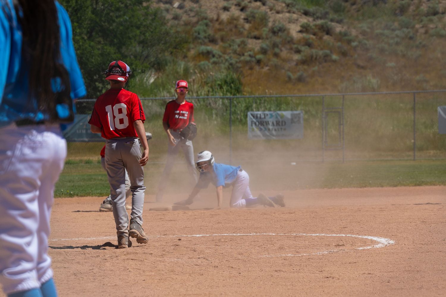 Baseball players in action during dusty infield play.