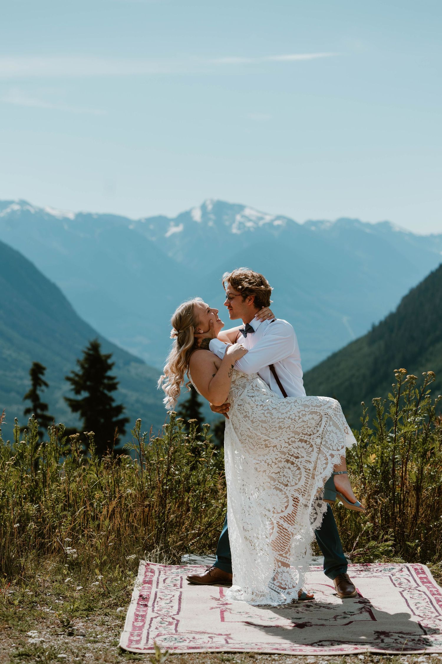 Couple dancing on decorative rug with majestic mountain range in background.