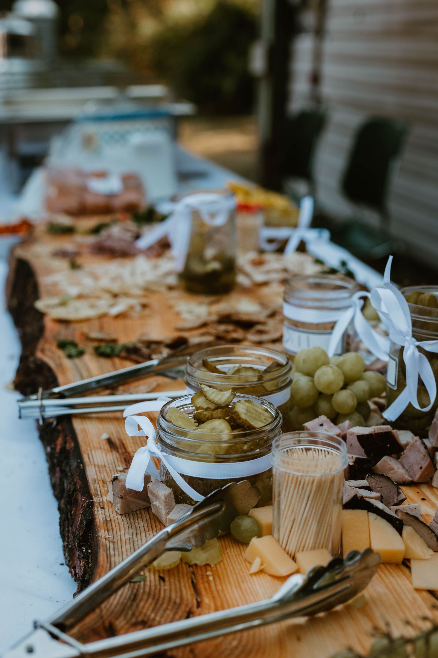 Rustic charcuterie board with pickles, grapes and appetizers at a wedding reception.