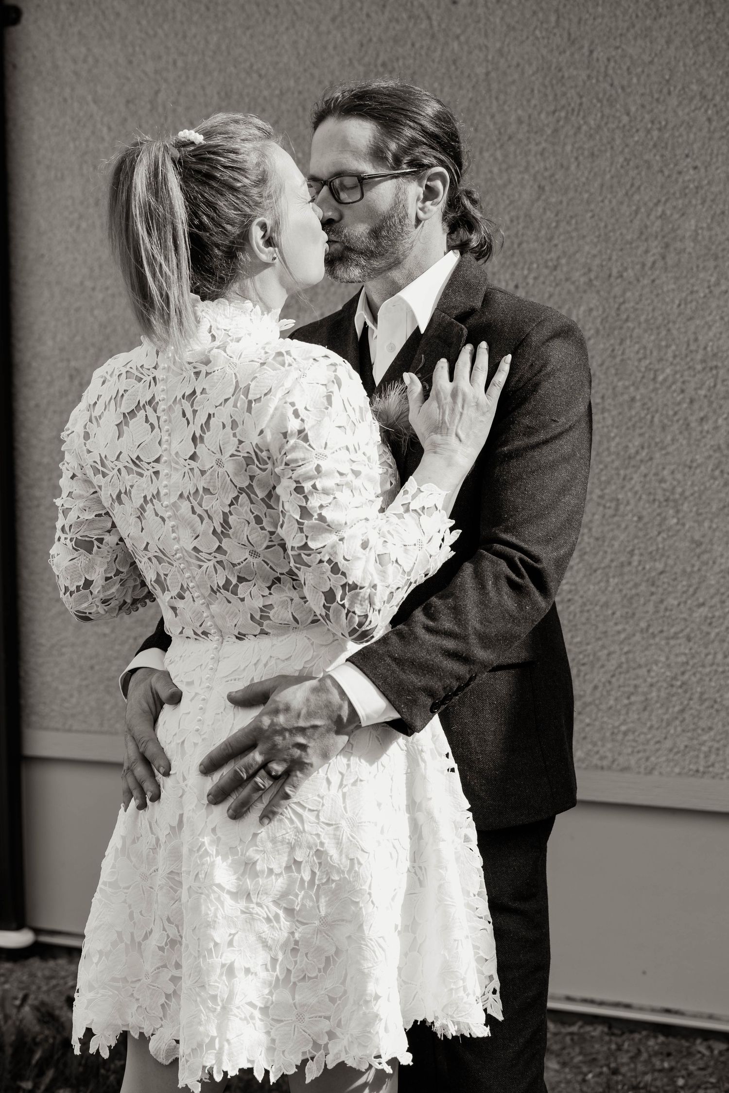 Black and white portrait of newlyweds embracing in formal wedding attire.