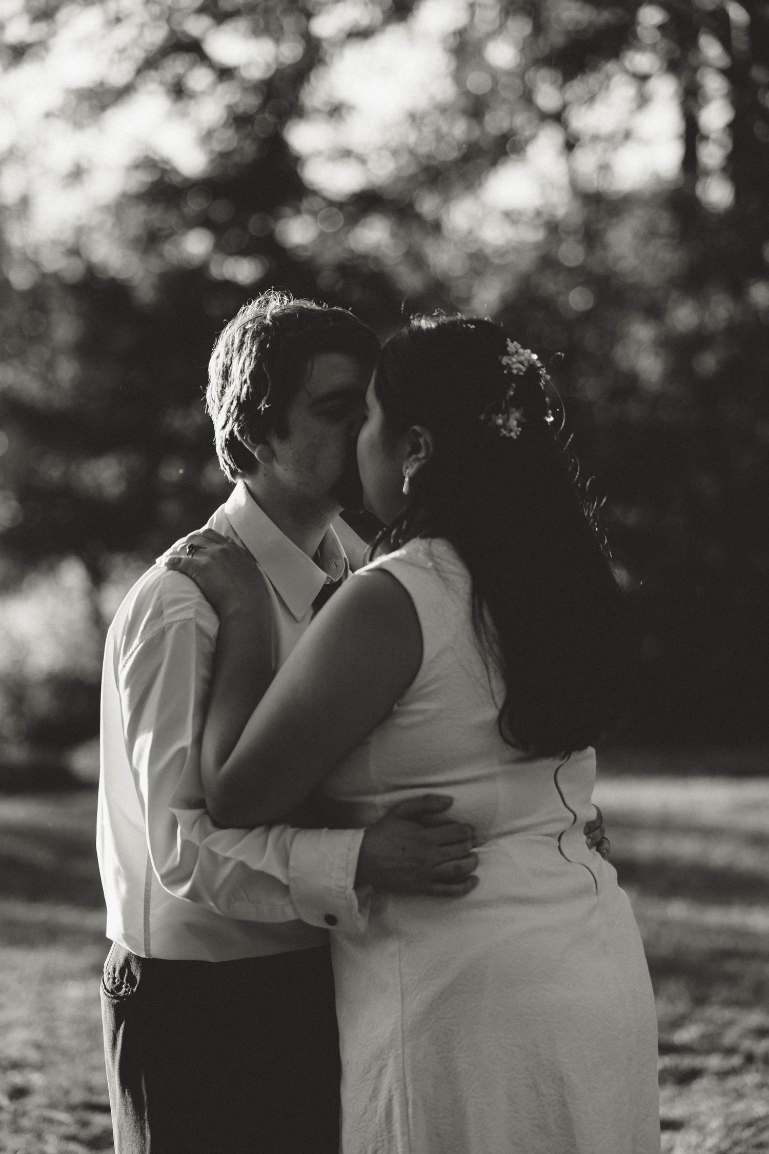 A romantic black and white portrait of a couple embracing outdoors.