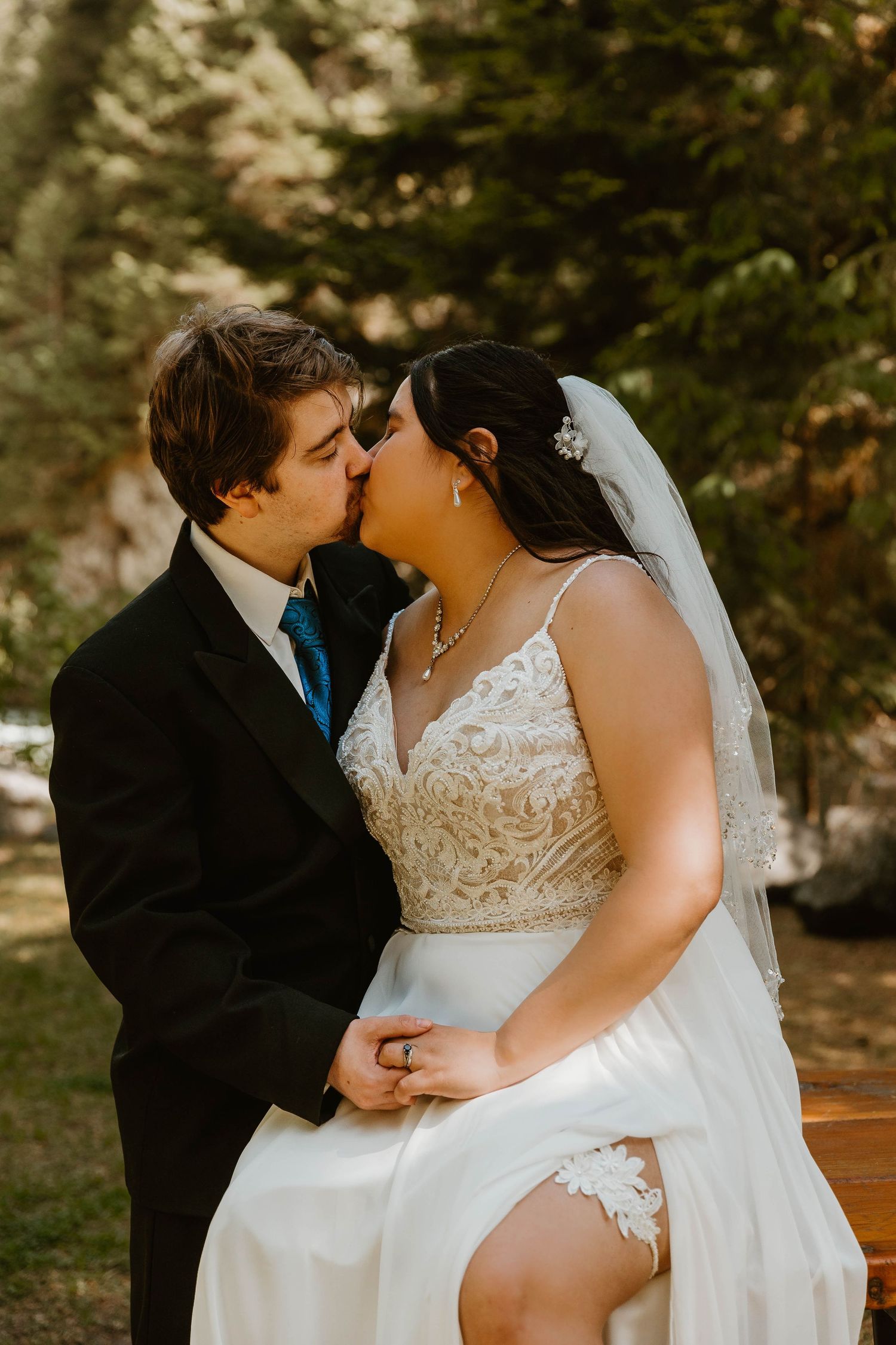 Romantic wedding couple shares intimate moment in sunlit forest setting.