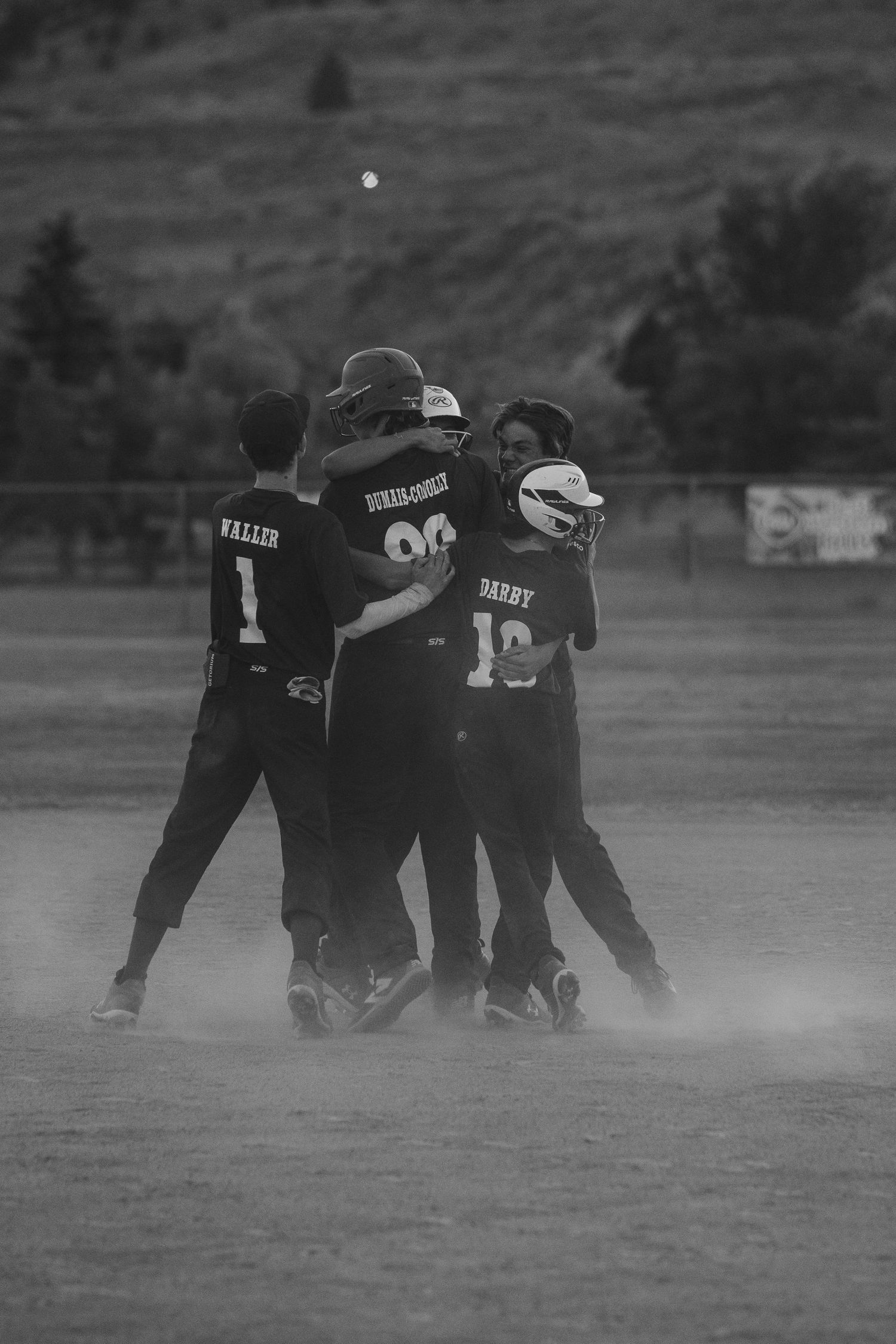 Black and white image of baseball players celebrating in team huddle on field.