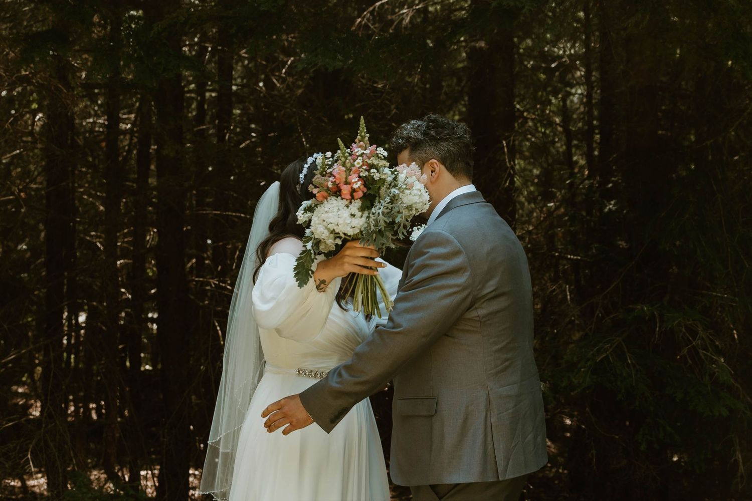Couple shares intimate moment during forest wedding ceremony.