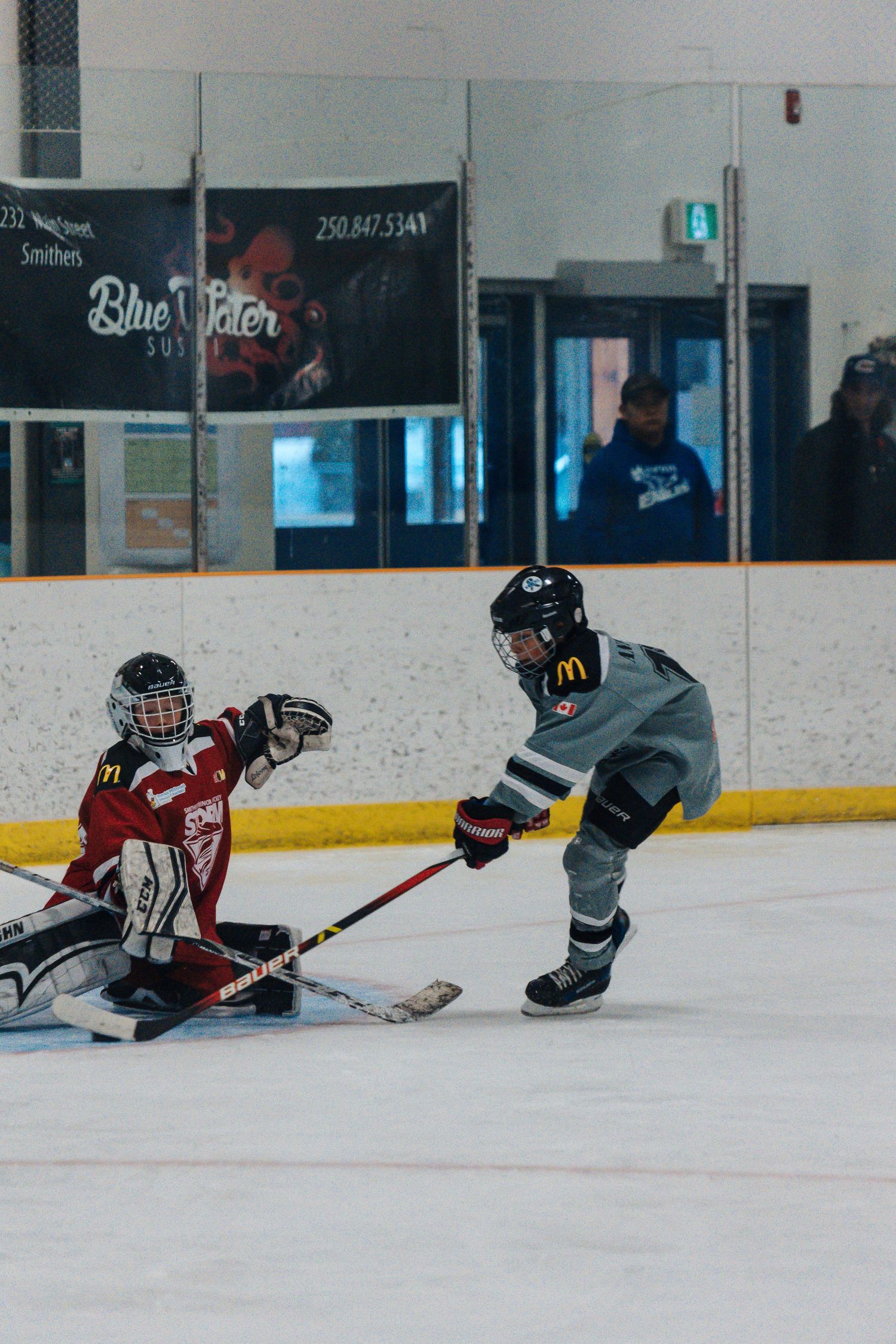 Two youth hockey players face off during an intense moment on the ice rink.