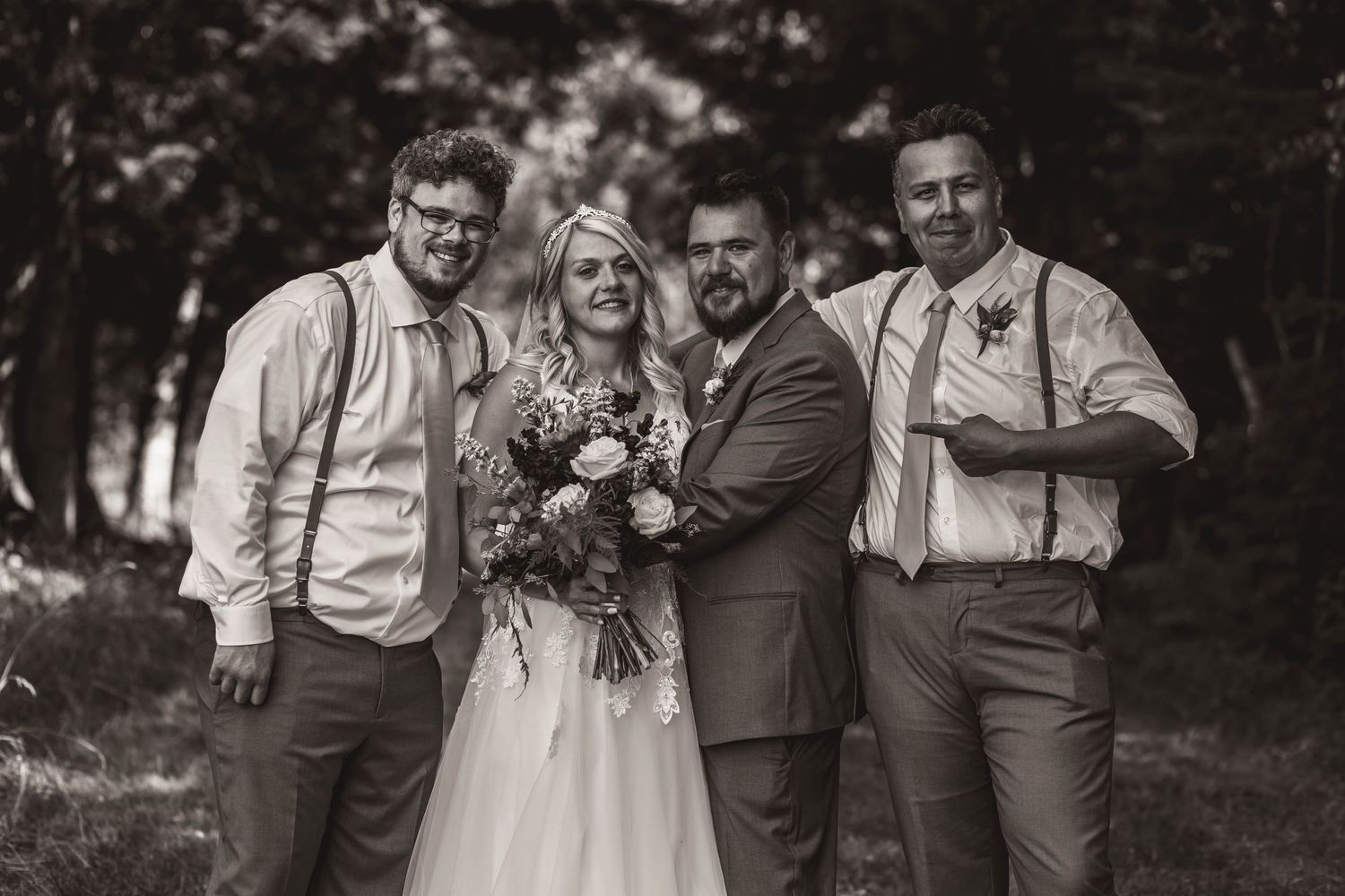 Black and white portrait of wedding party in rustic outdoor setting.