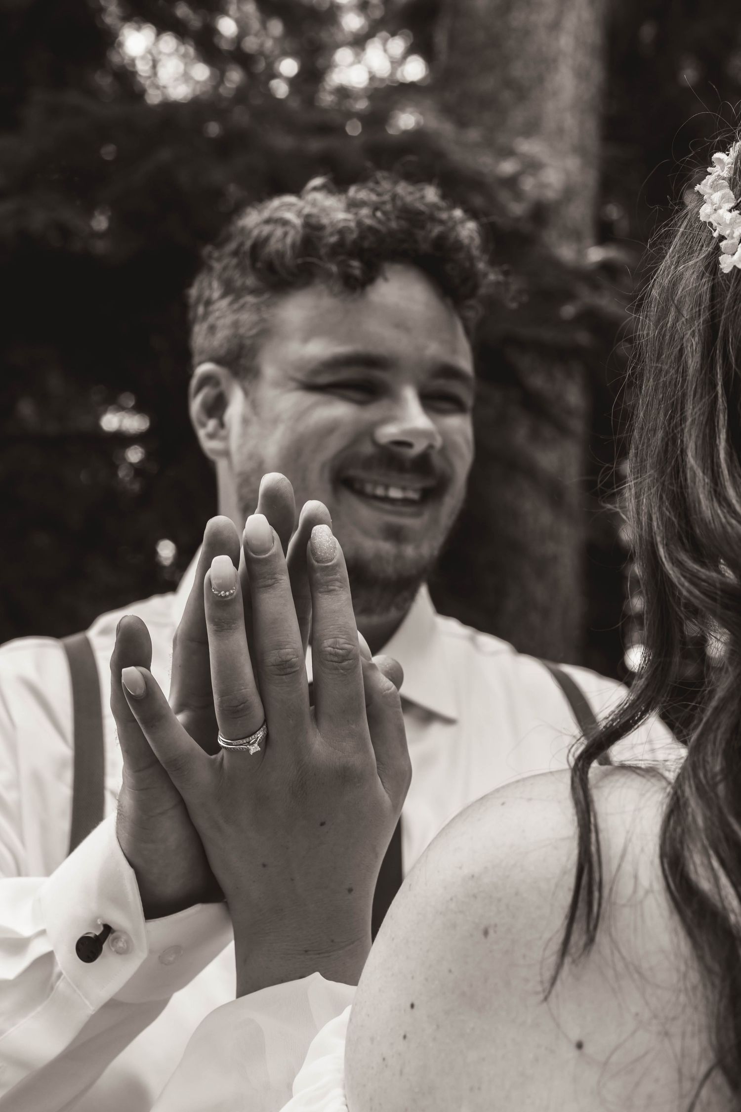 Close-up of wedding rings being shown off during outdoor celebration.